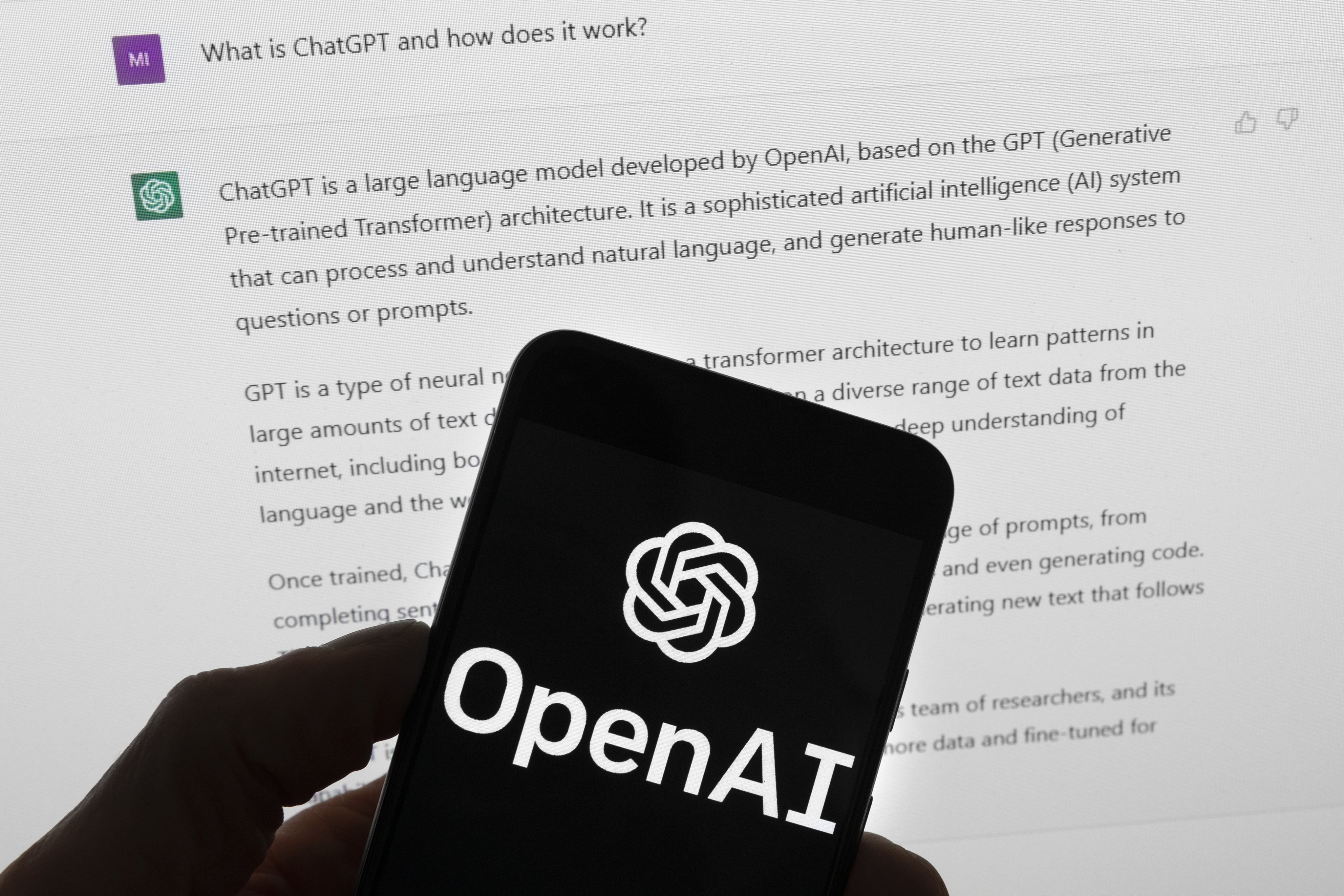 The OpenAI logo seen on a mobile phone in front of a computer screen displaying output from ChatGPT on March 21, 2023. Photo: AP