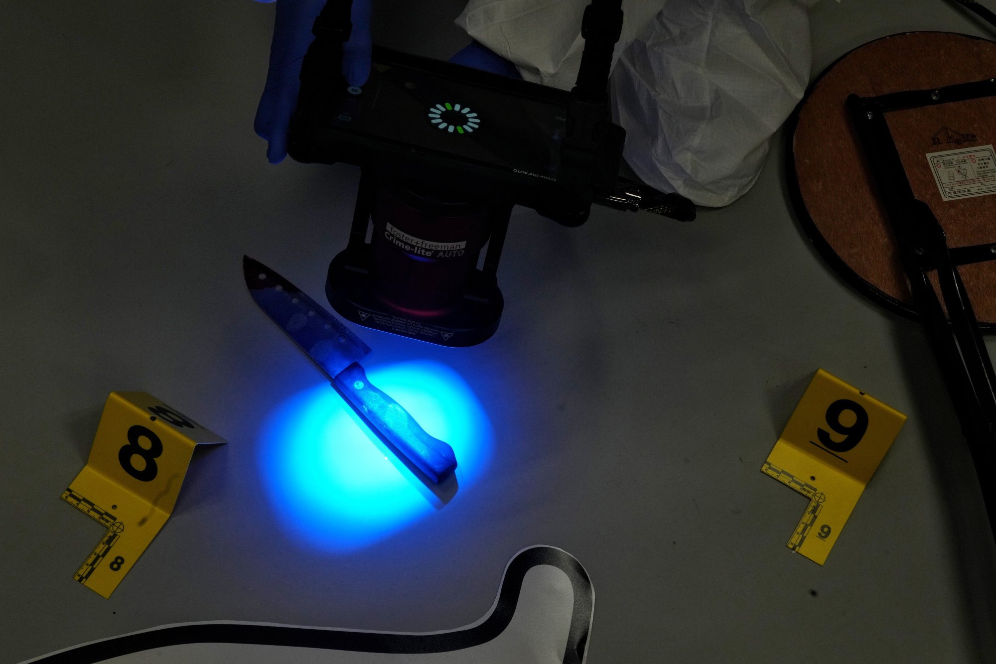 A forensic examiner demonstrates a special light used to find fingerprints on evidence. Photo: Elson Li