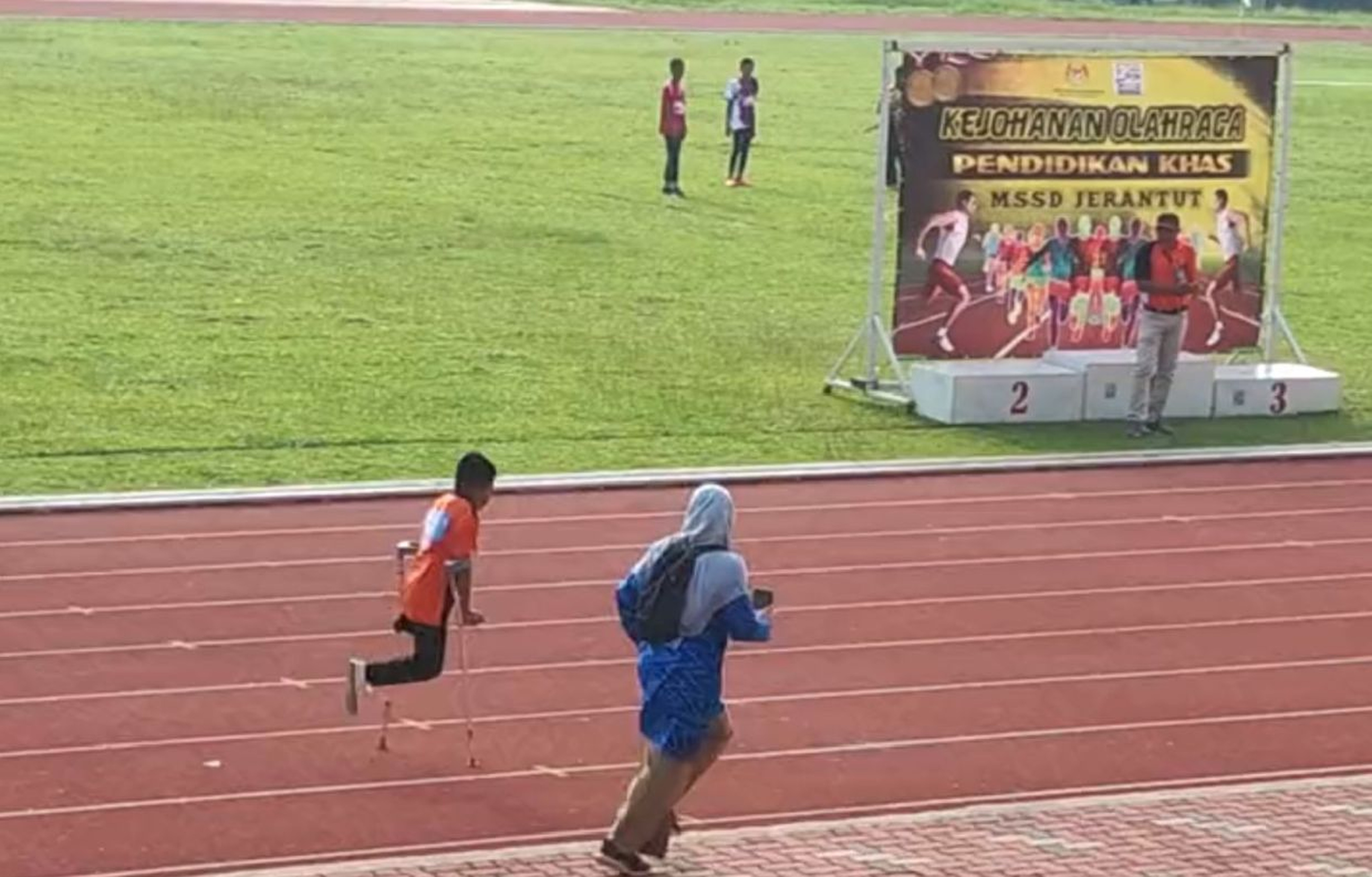 A teacher is seen running alongside her student to encourage him to cross the finish line at a Malaysian school sports event. Photo: TikTok/@faridkamaruddin18