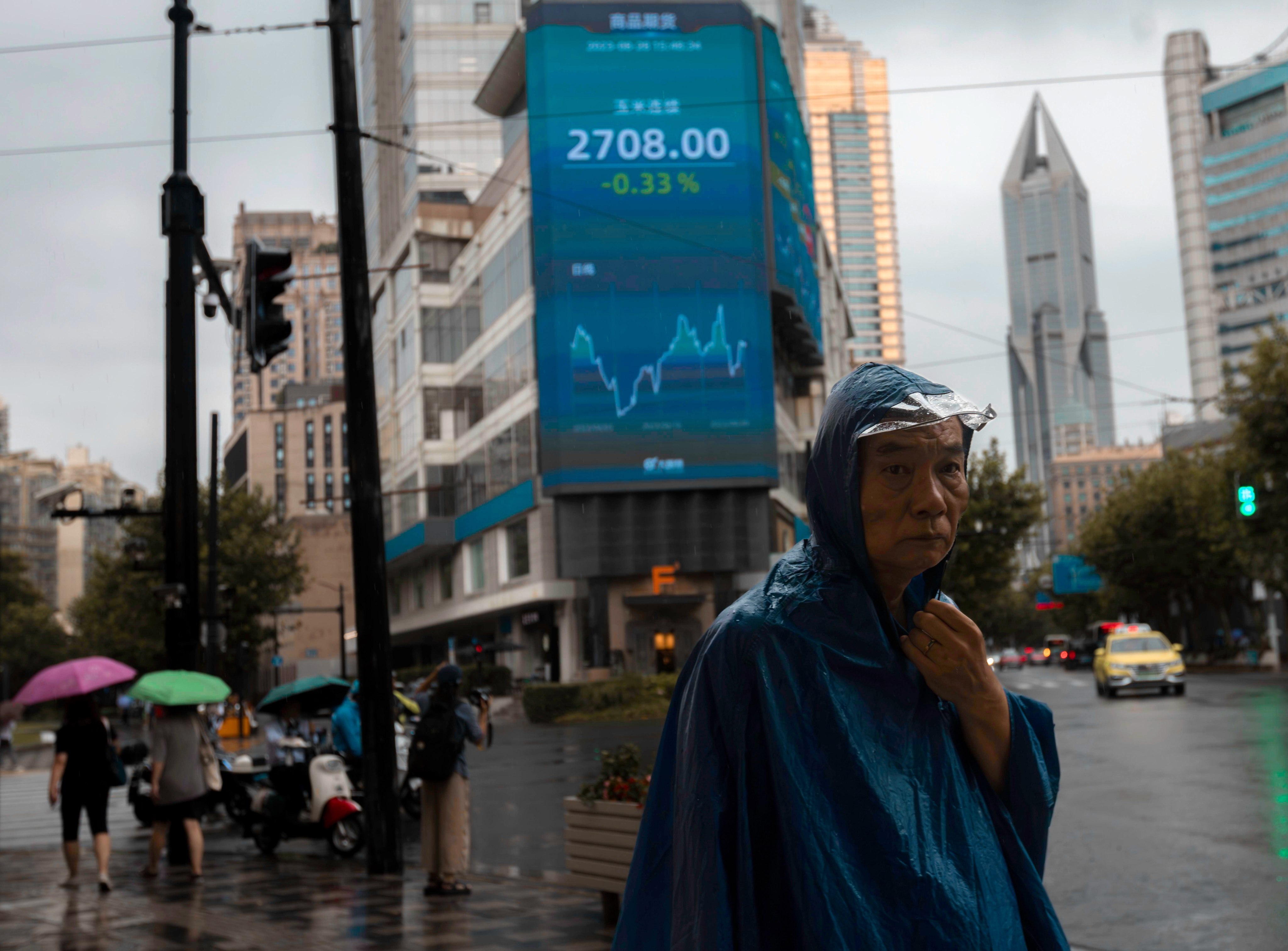 A man walks on the street, in front of the large screen displaying the latest stock exchange data, in Shanghai on August 28. Photo: EPA-EFE
