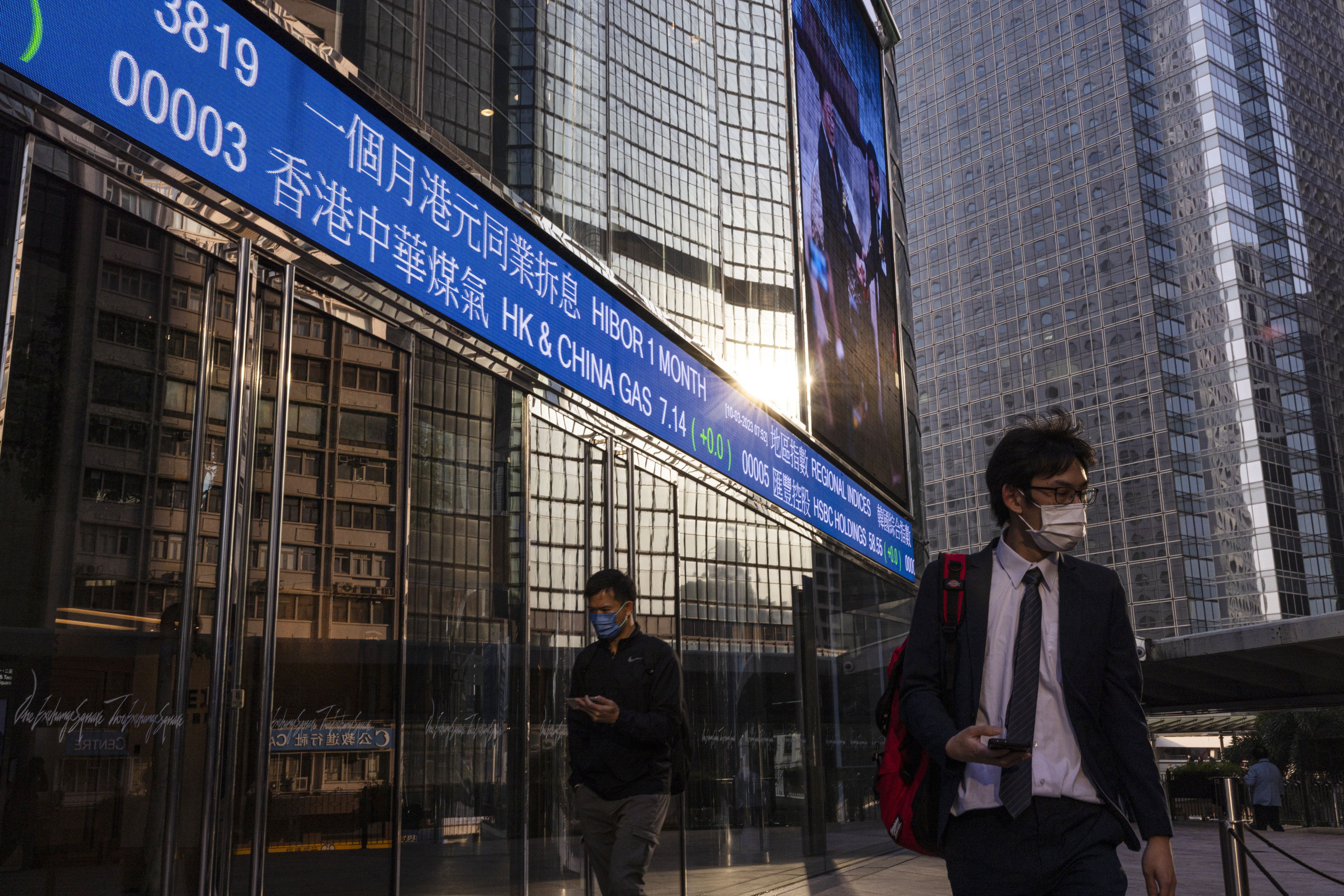 People walk past an electronic screen in Central, Hong Kong on March 10, 2023. Photo: AP
