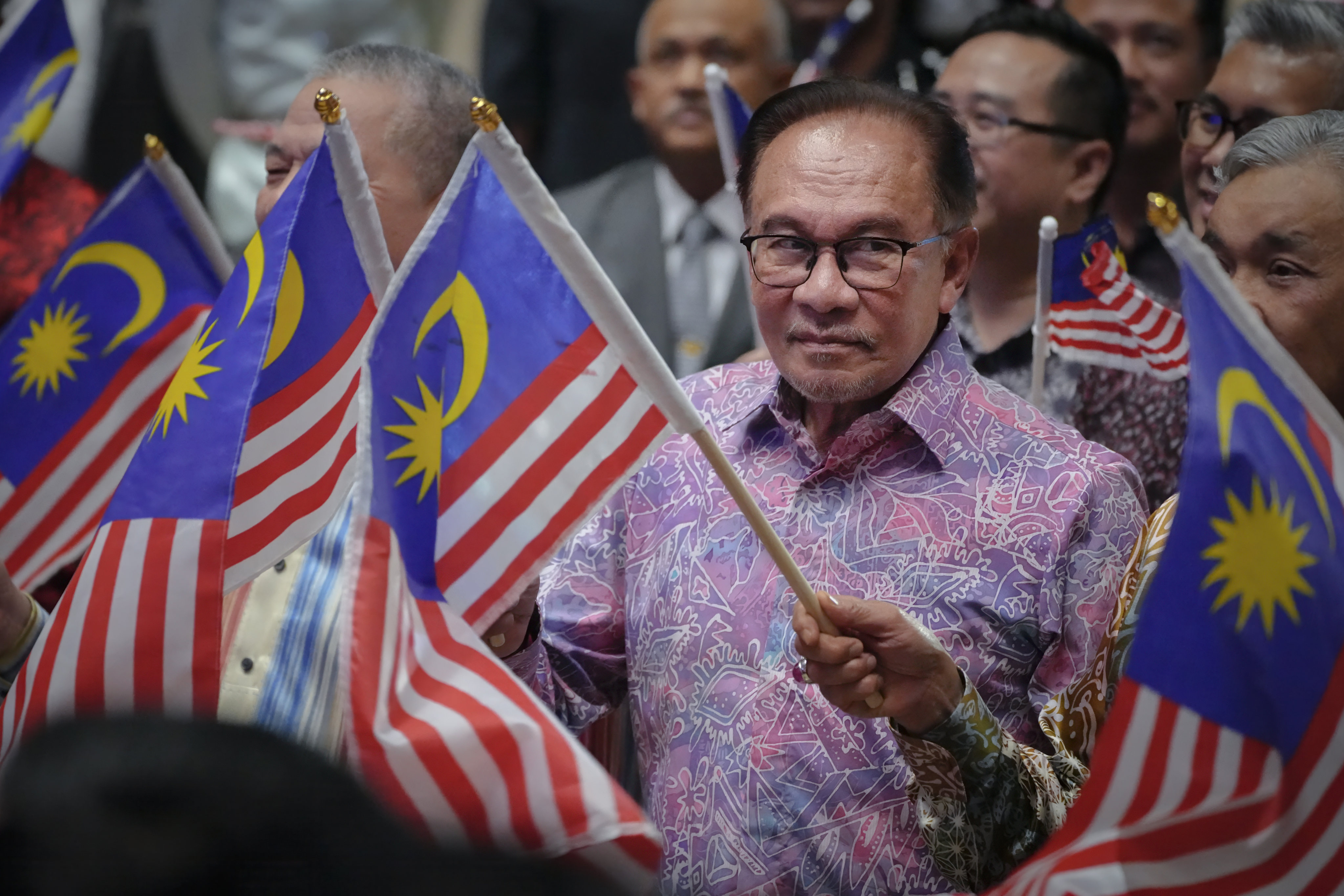 Malaysian Prime Minister Anwar Ibrahim waves the national flag after delivering his speech for National Day on Wednesday. Photo: AP