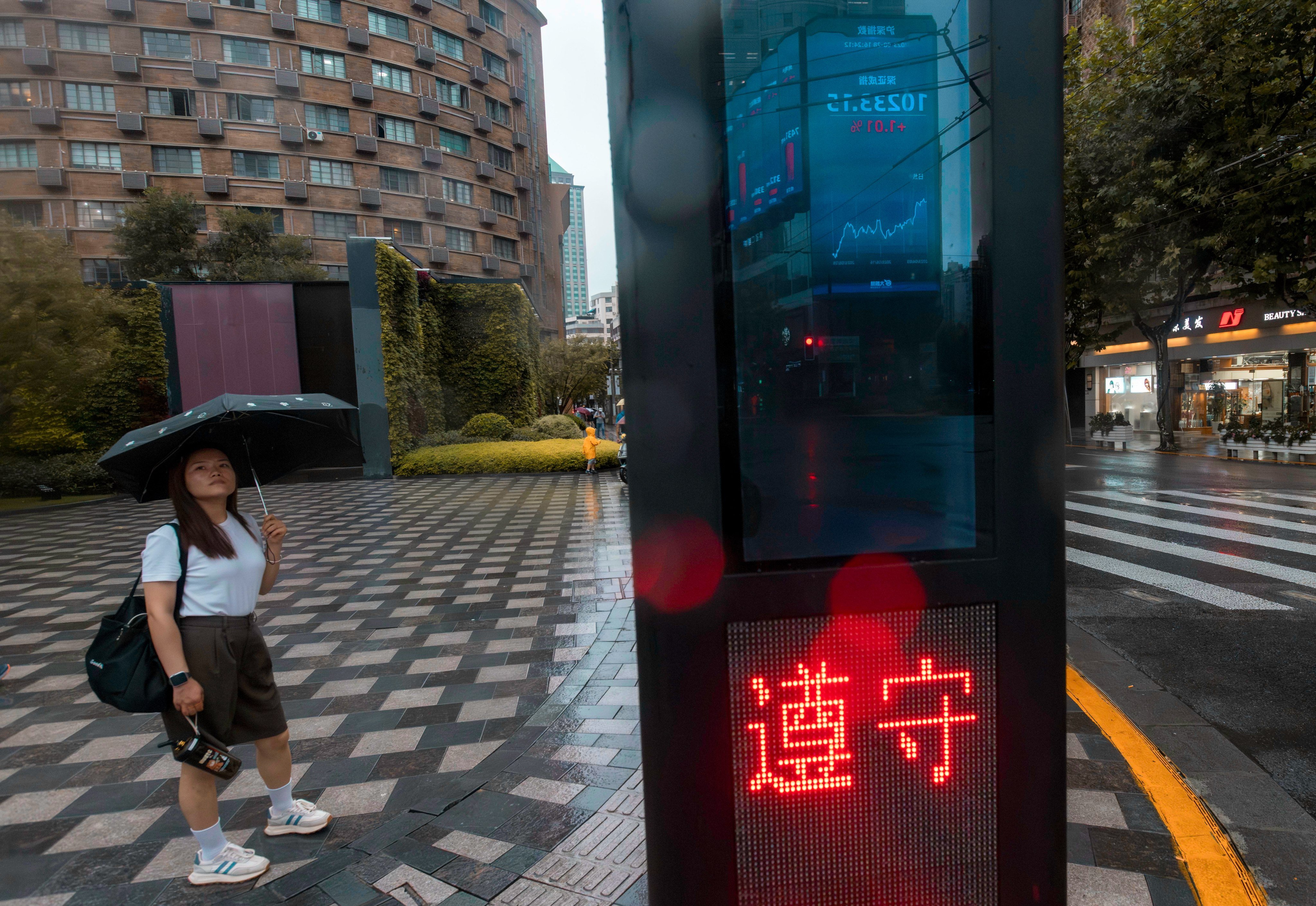 A screen displaying the latest stock exchange data is reflected in a traffic light post, in Shanghai, on August 28. Investors must take the probabilities of what they think the mainland economic authorities will do and decide to buy now or hold off. Photo: EPA-EFE