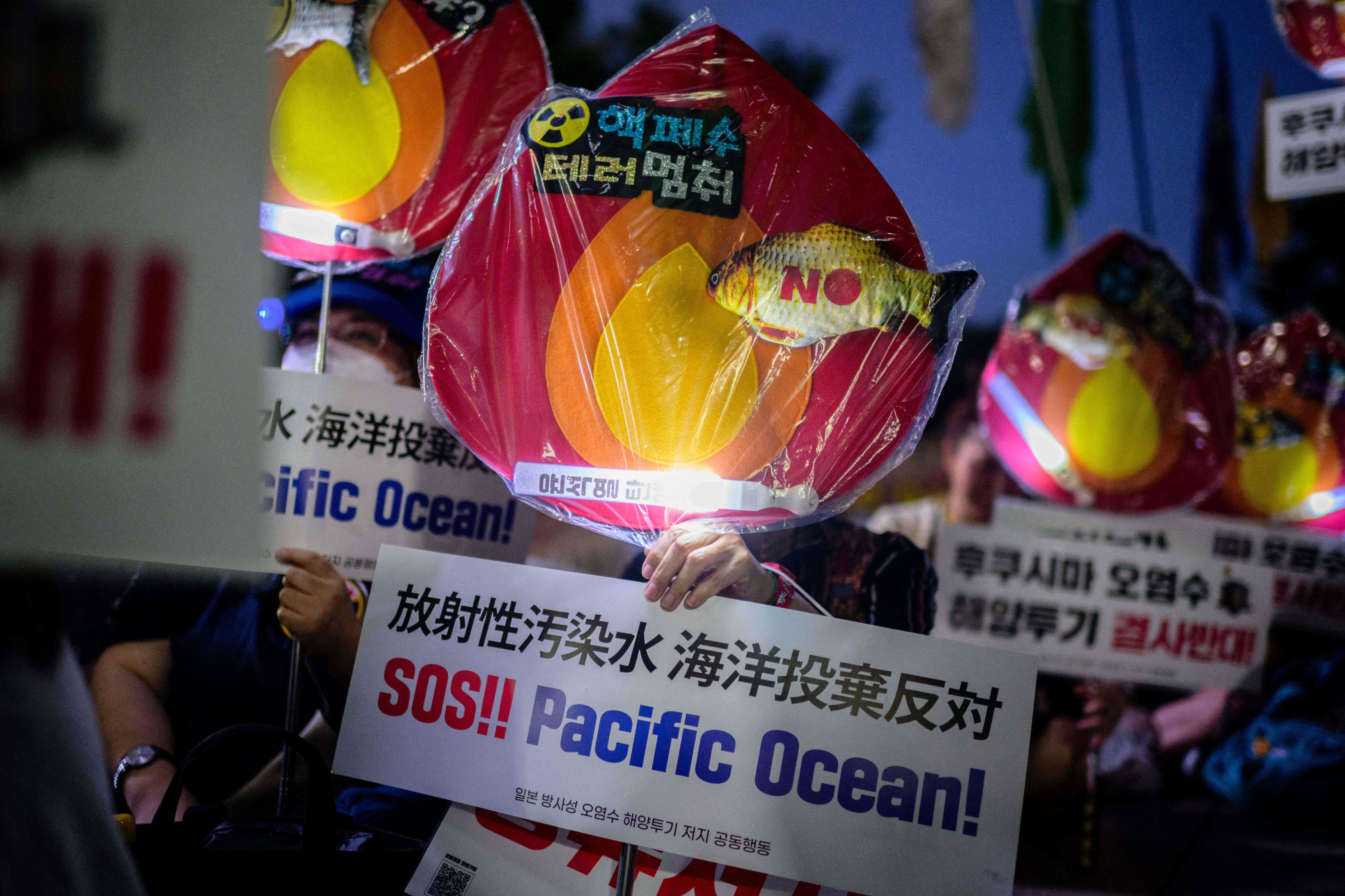 An activist holds a sign that reads “SOS!! Pacific Ocean!” during a protest outside City Hall in Seoul, South Korea on August 22, 2023 against the planned release of waste water from Japan’s Fukushima nuclear plant into the ocean. Photo: AFP