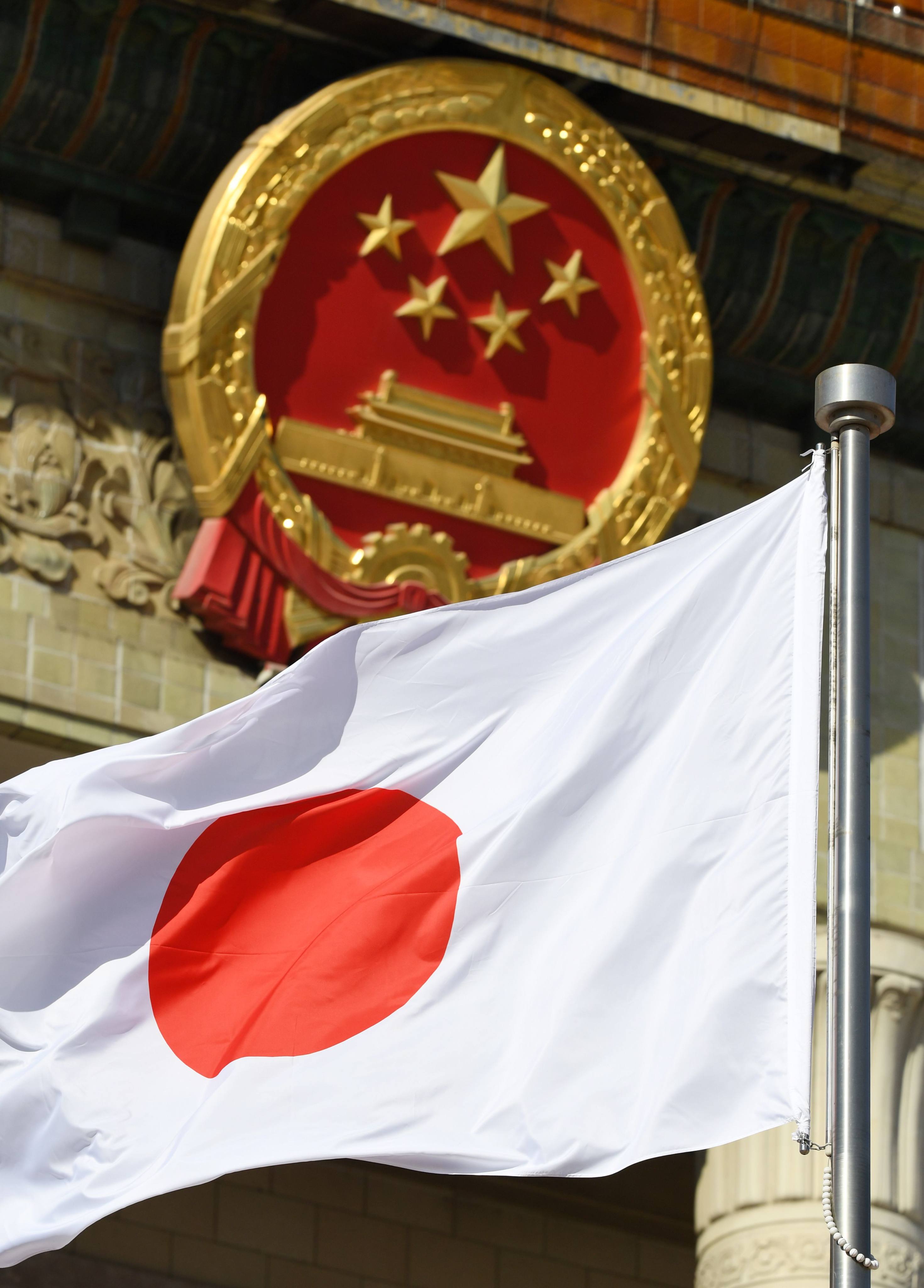 The Japanese flag flies near the emblem of the People’s Republic of China. Photo: AFP