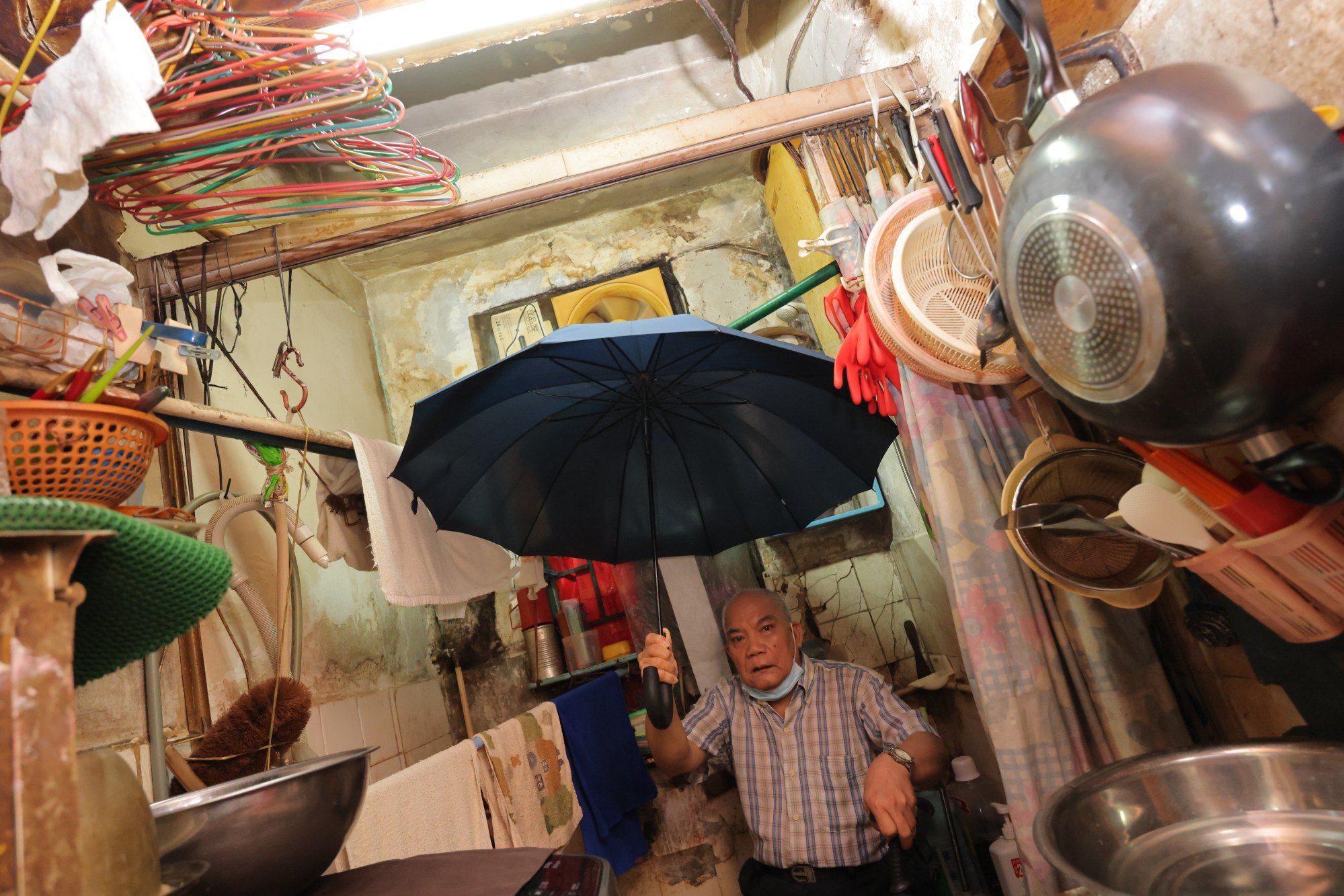 Luk Kui-to is forced to use an umbrella in his toilet when it rains because of leaks in his building. Photo: Jelly Tse