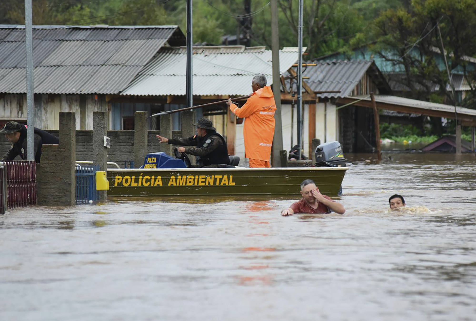 Police check a house as residents wade through a flooded street after floods caused by a cyclone in Passo Fundo, Rio Grande do Sul state, Brazil on Monday. Photo: AP 