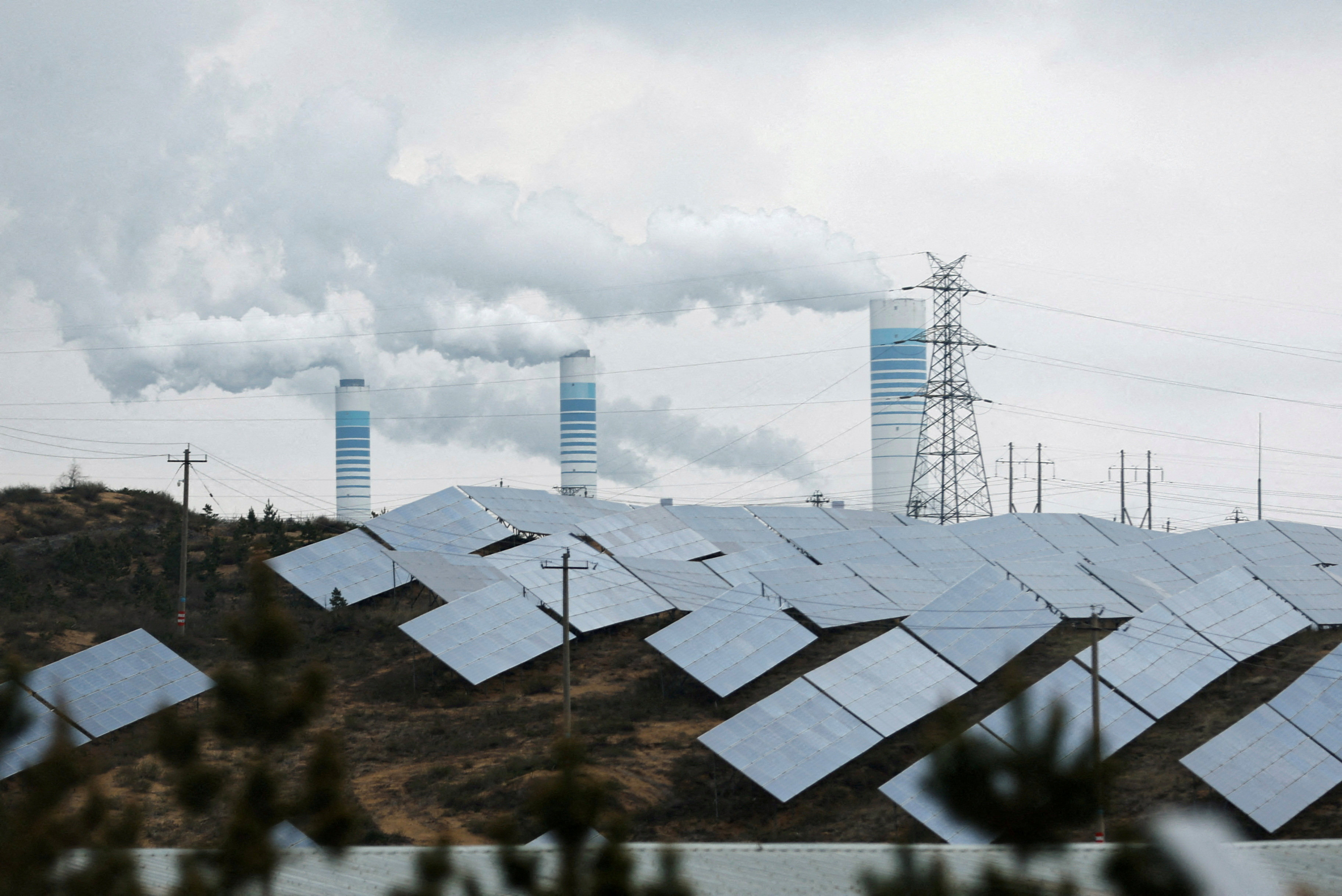 Smoke rises from chimneys near solar panels in Shaanxi province, China on April 24, 2023. Photo: Reuters