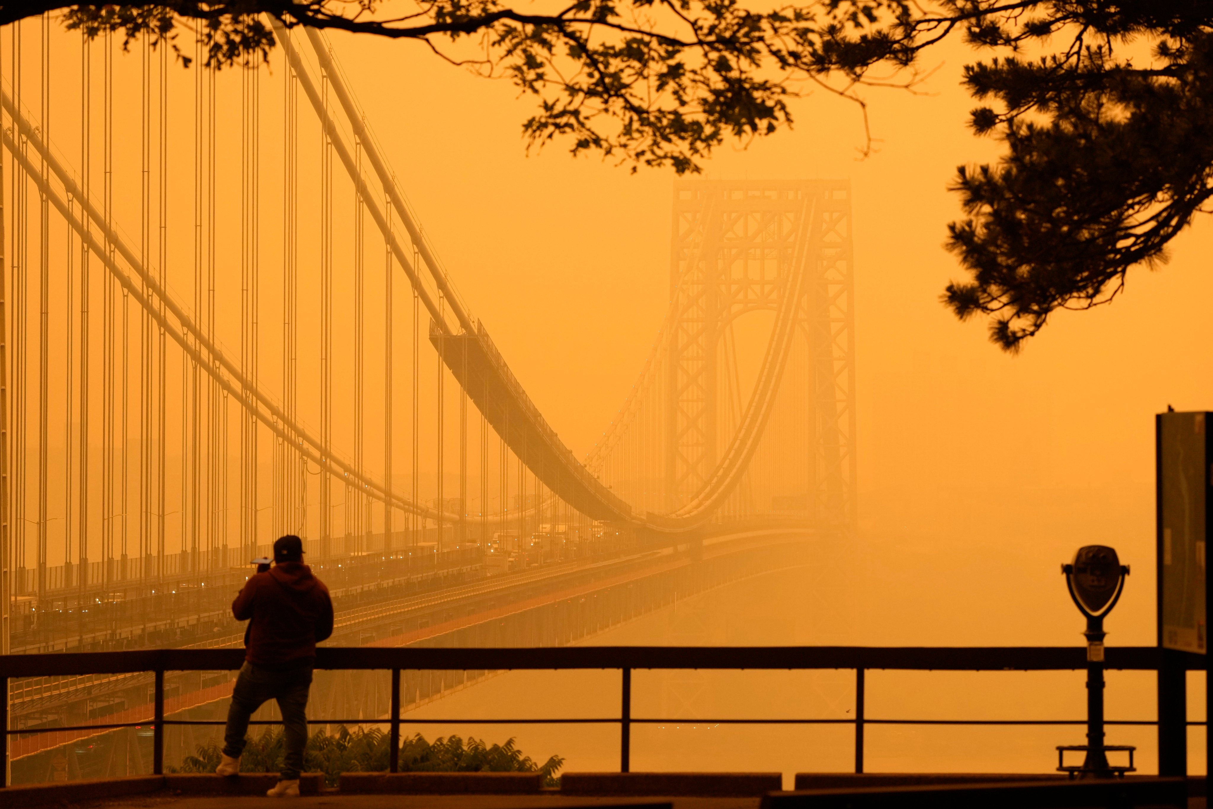 A  man talks on his phone as he looks through the haze at the George Washington Bridge from Fort Lee, New Jersey, on June 7 when intense Canadian wildfires blanketed the northeastern US in a dystopian haze. Photo: AP 