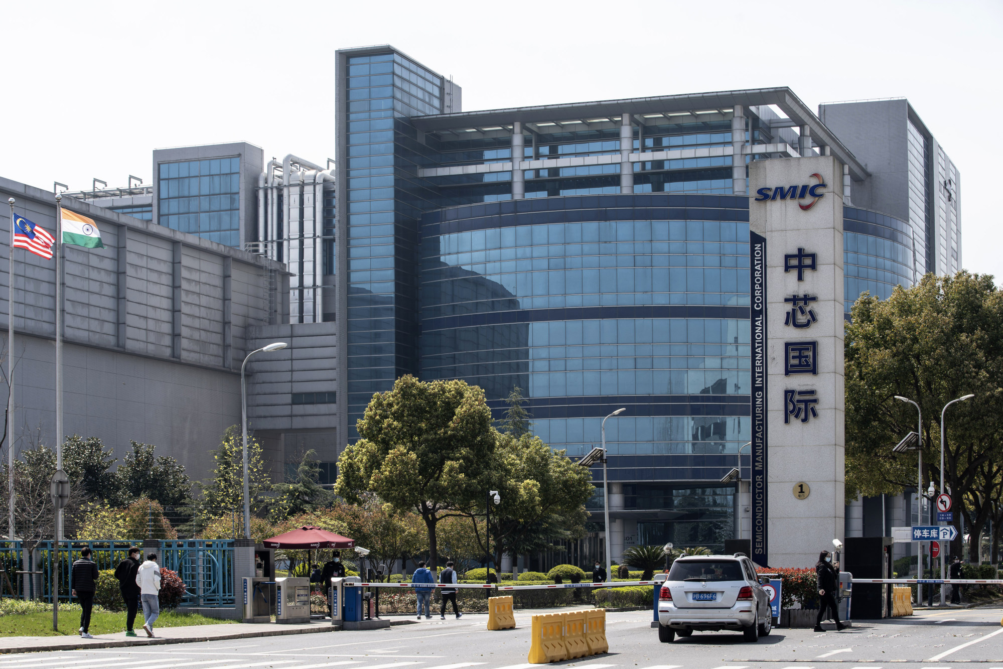  The image shows the headquarters of Semiconductor Manufacturing International Corporation (SMIC), a Chinese semiconductor company, with the US and Indian flags flying outside. The image represents the search query 'US export licenses for Huawei and SMIC' because both companies have faced scrutiny from the US government over their alleged ties to the Chinese military.