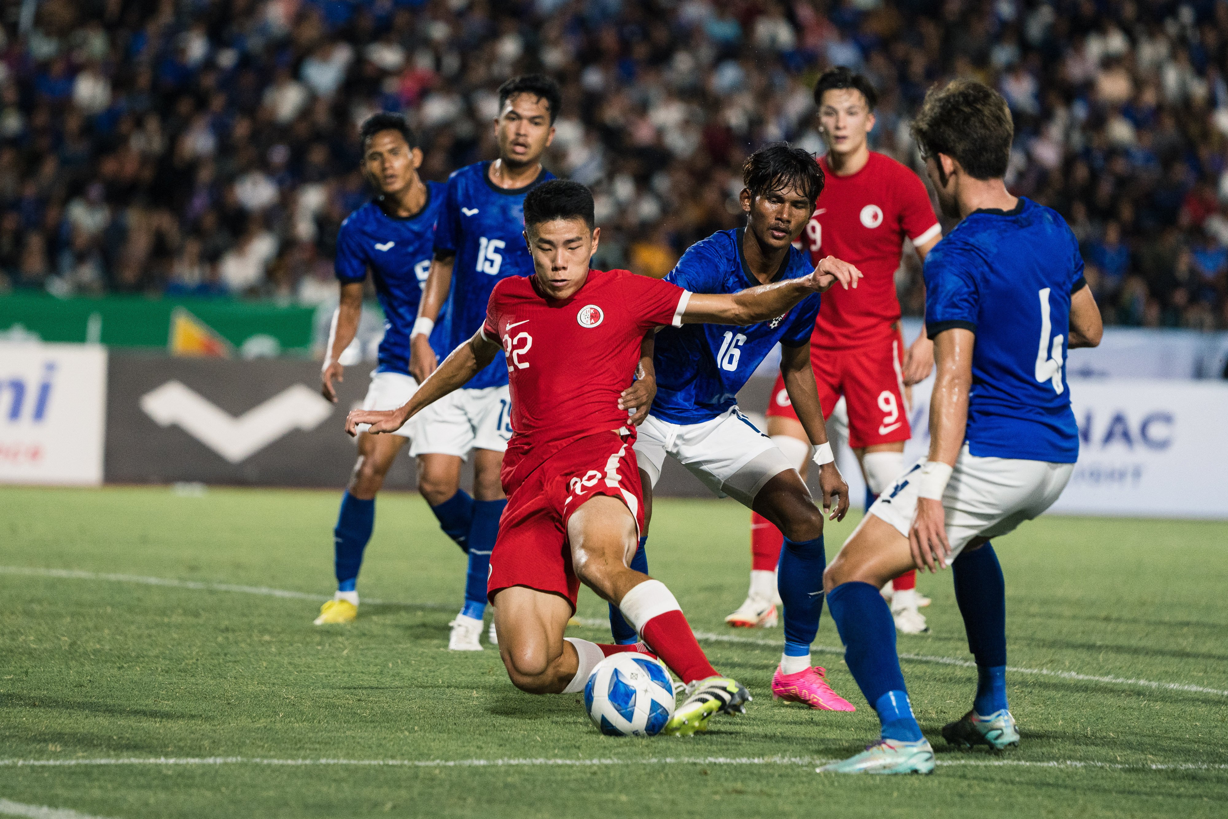 Hong Kong forward Sun Ming-him tries to stay on his feet as the Cambodia defence closes in. Photo: HKFA