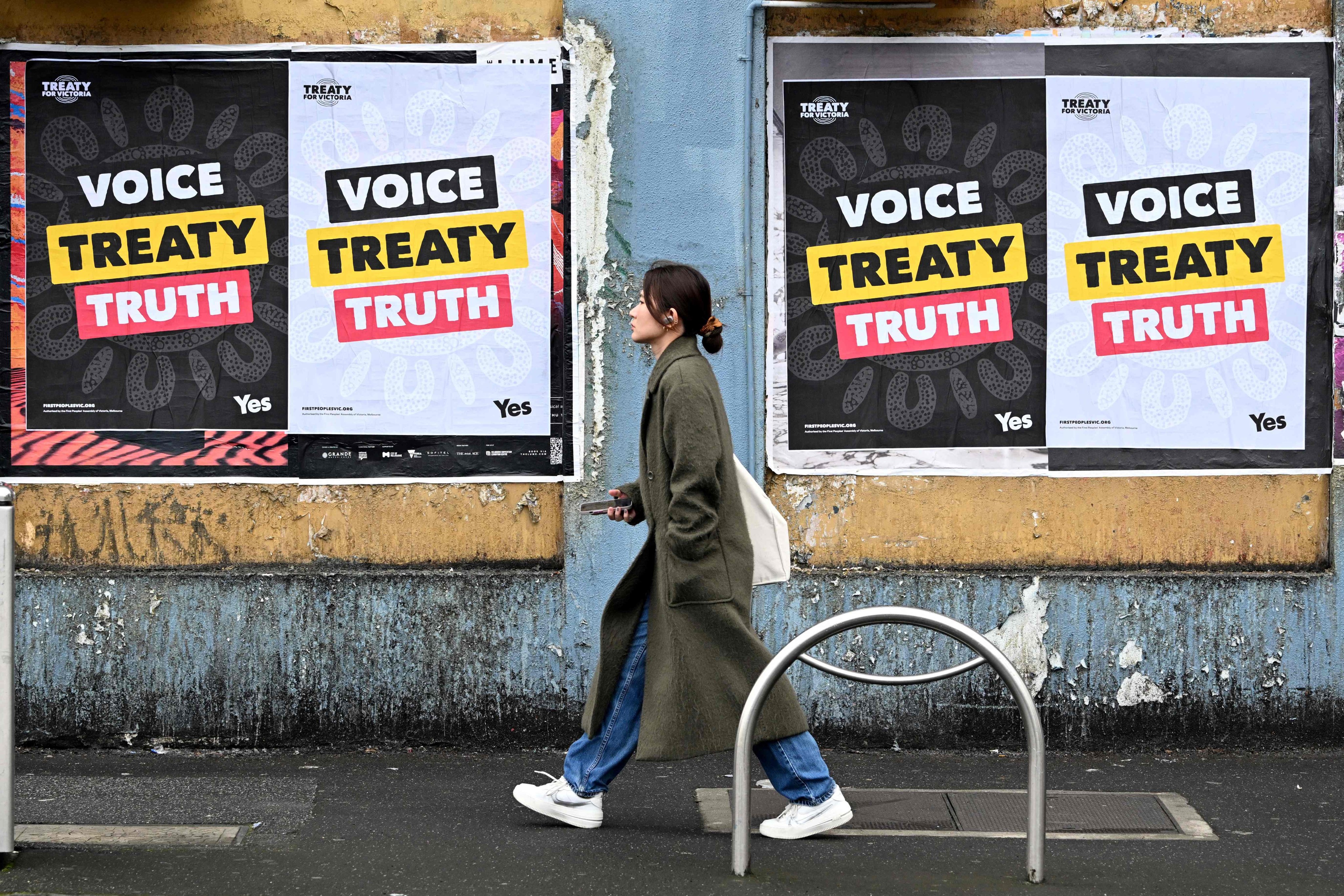 A woman in Melbourne walks past posters advocating for a voice for indigenous peoples. Photo: AFP 