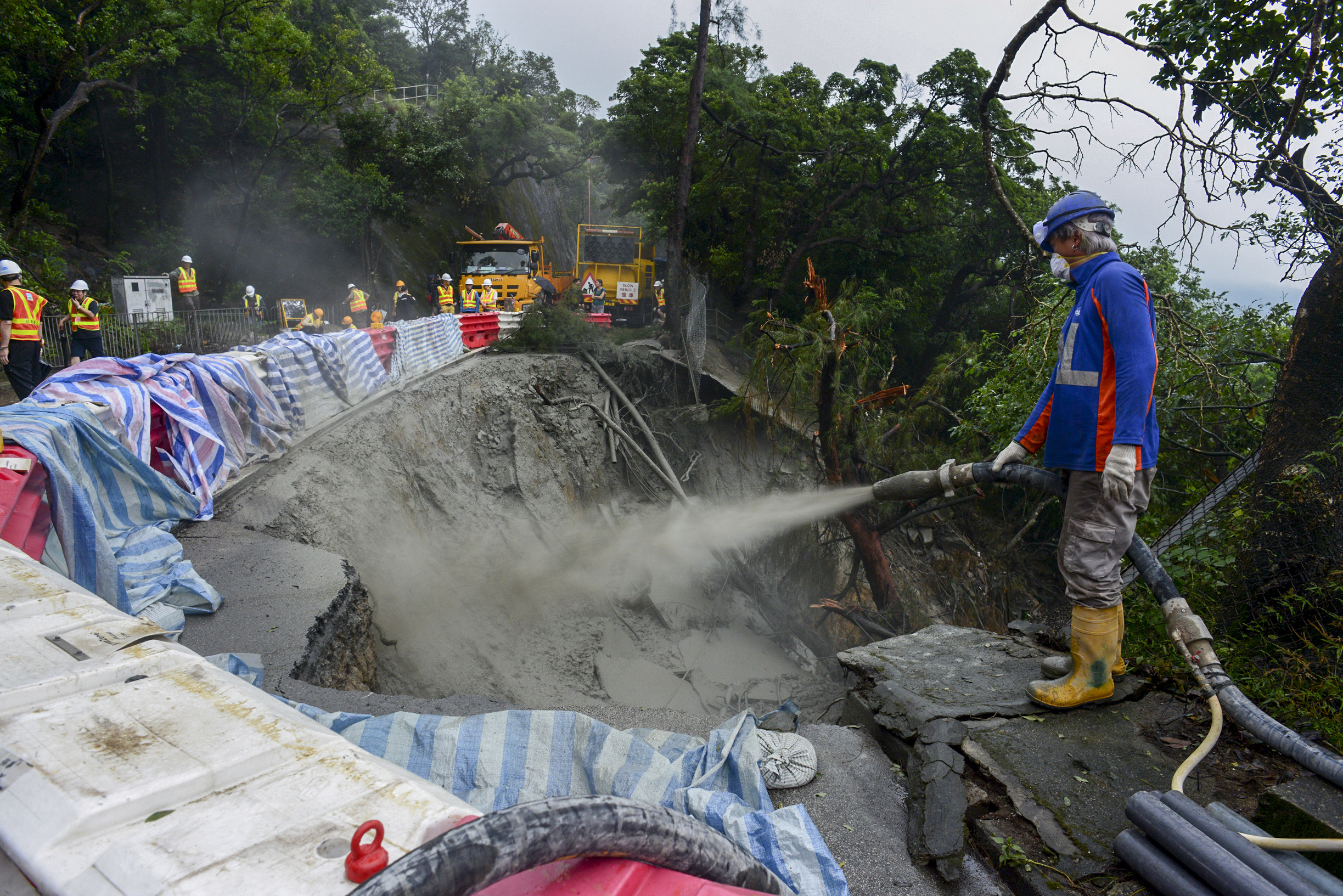 Workers begin repairing the road out of Shek O village on Hong Kong Island. Photo: Antony Dickson