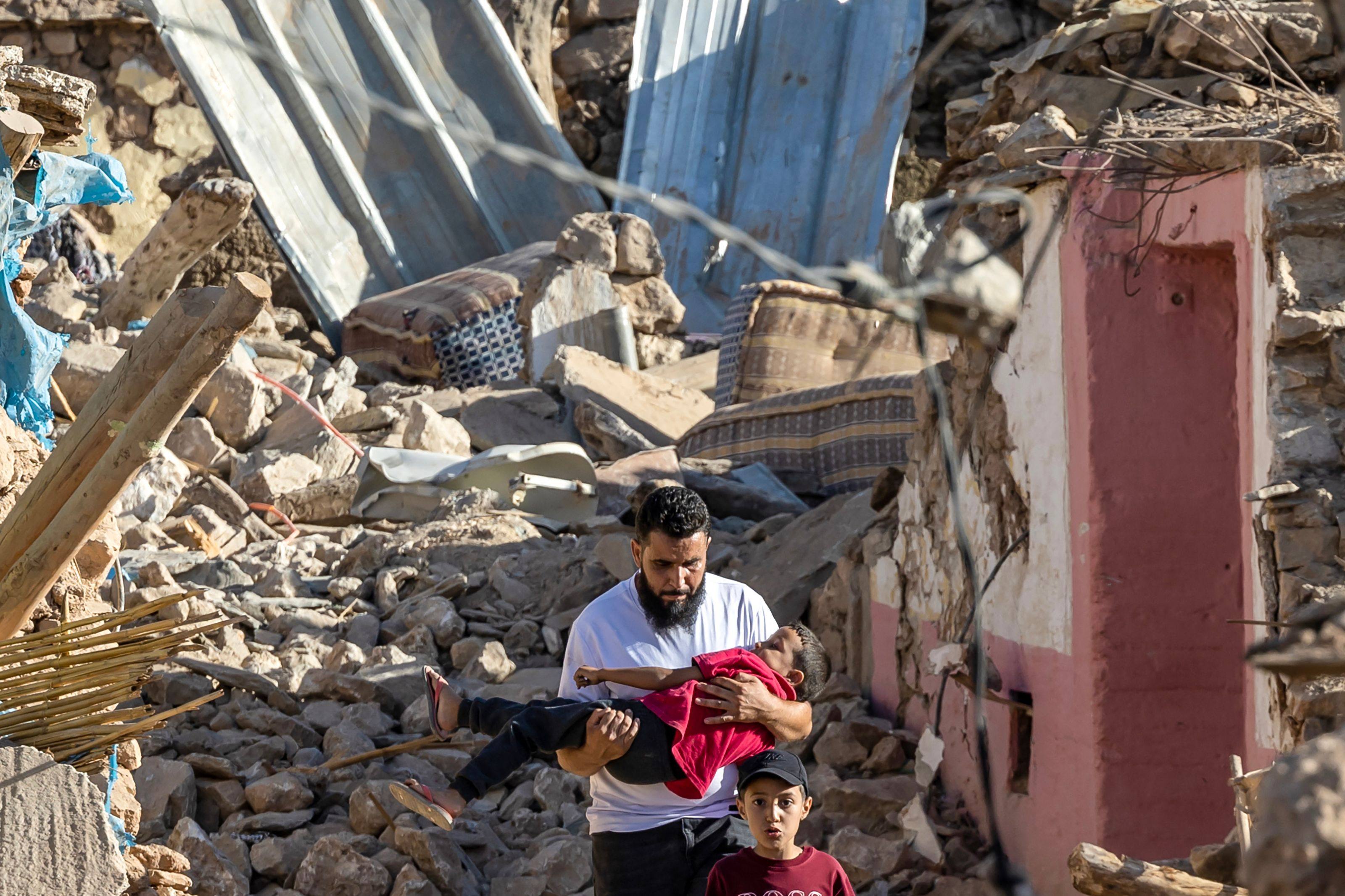 A man carries a boy past destroyed homes after an earthquake in Morocco. Photo: AFP