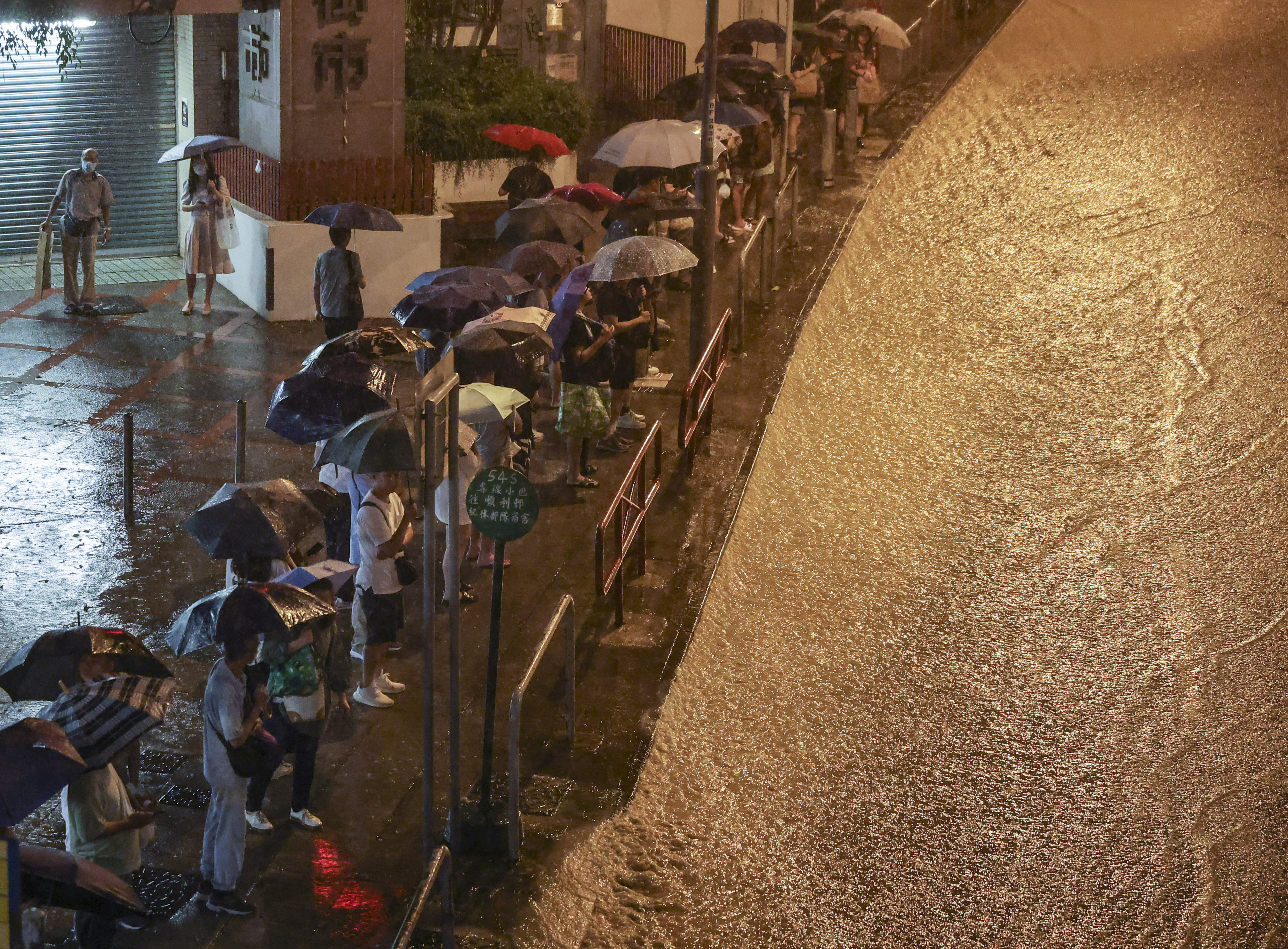 People queue at a bus stop as a road in Choi Hung, Hong Kong, turns into a torrent. Photo: Edmond So
