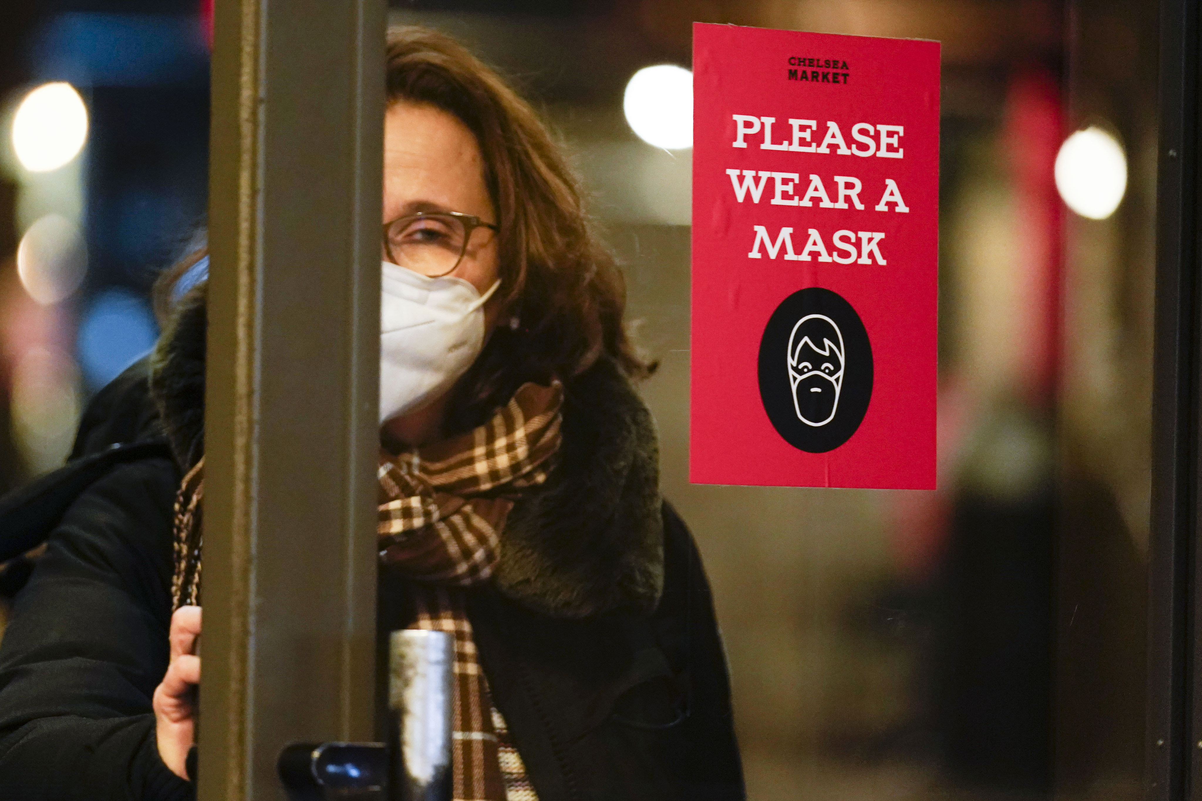 A woman walks through a door with a sign asking shoppers to wear masks in New York on February 9, 2022. The lengthy deliberations over a globally binding pandemic treaty and the watering down of the draft’s language suggests the lessons of Covid-19 are being ignored or forgotten. Photo: AP