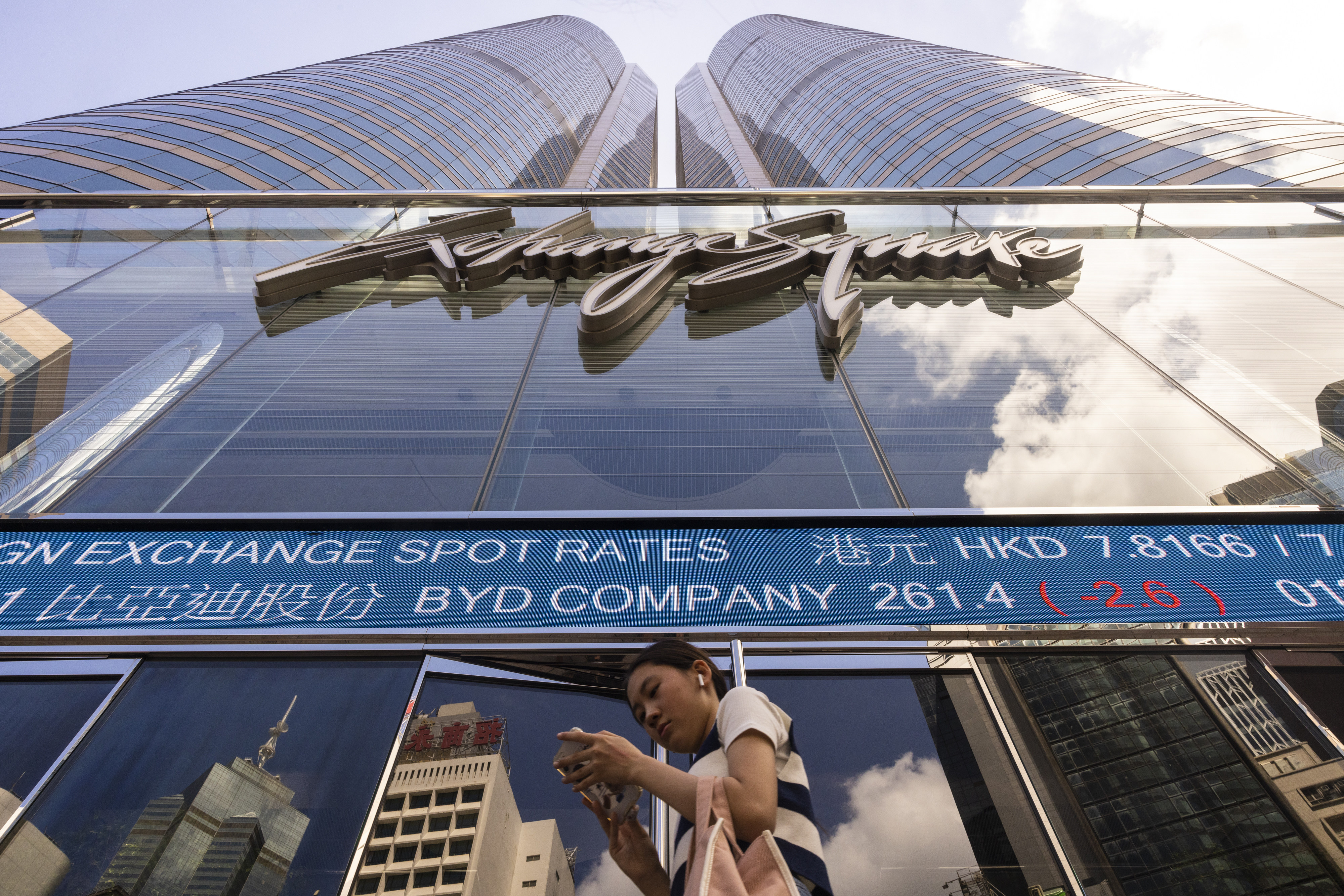 A pedestrian passes by the Hong Kong Stock Exchange electronic screen in July 2023. Photo: AP