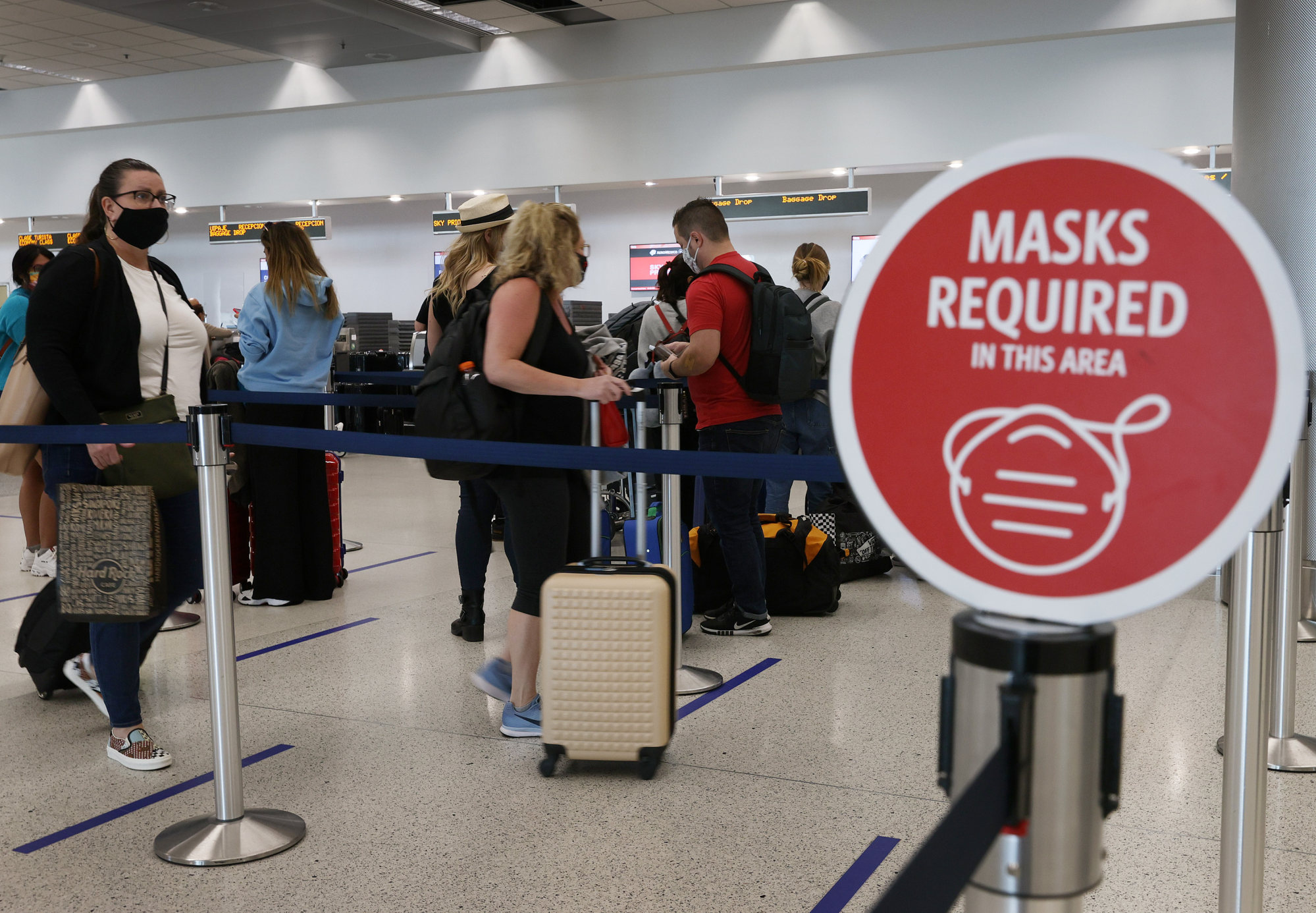 A sign reading, “Masks required in this area” is seen as travellers prepare to check in at the Miami International Airport in Florida in February 2021. Photo: Getty Images/TNS
