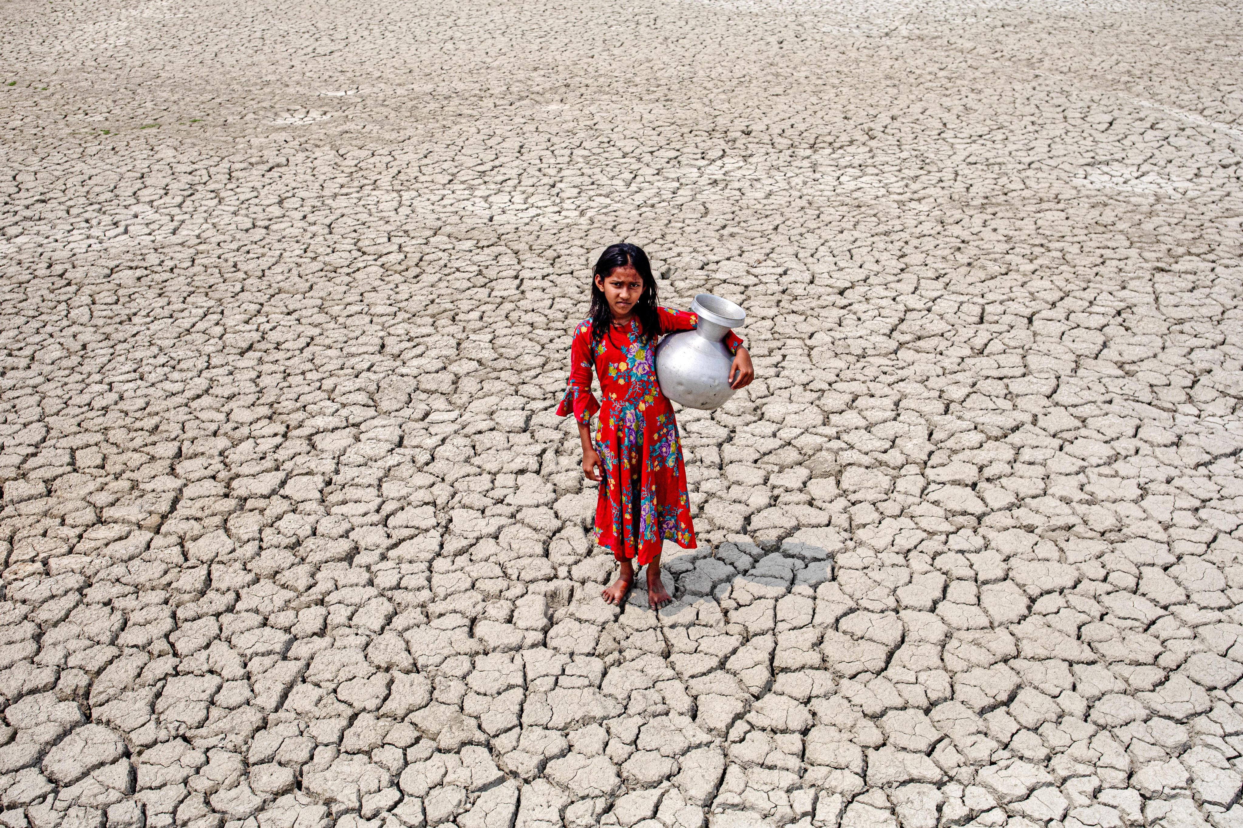 A gril walks into a deep cracks field after collecting drinking water from a pond near mangrove forest Sundarban in Satkhira, Bangladesh on March 27, 2022.  (Photo by Kazi Salahuddin Razu/NurPhoto via Getty Images)&#xA;&#xA;CREDIT: Getty Images