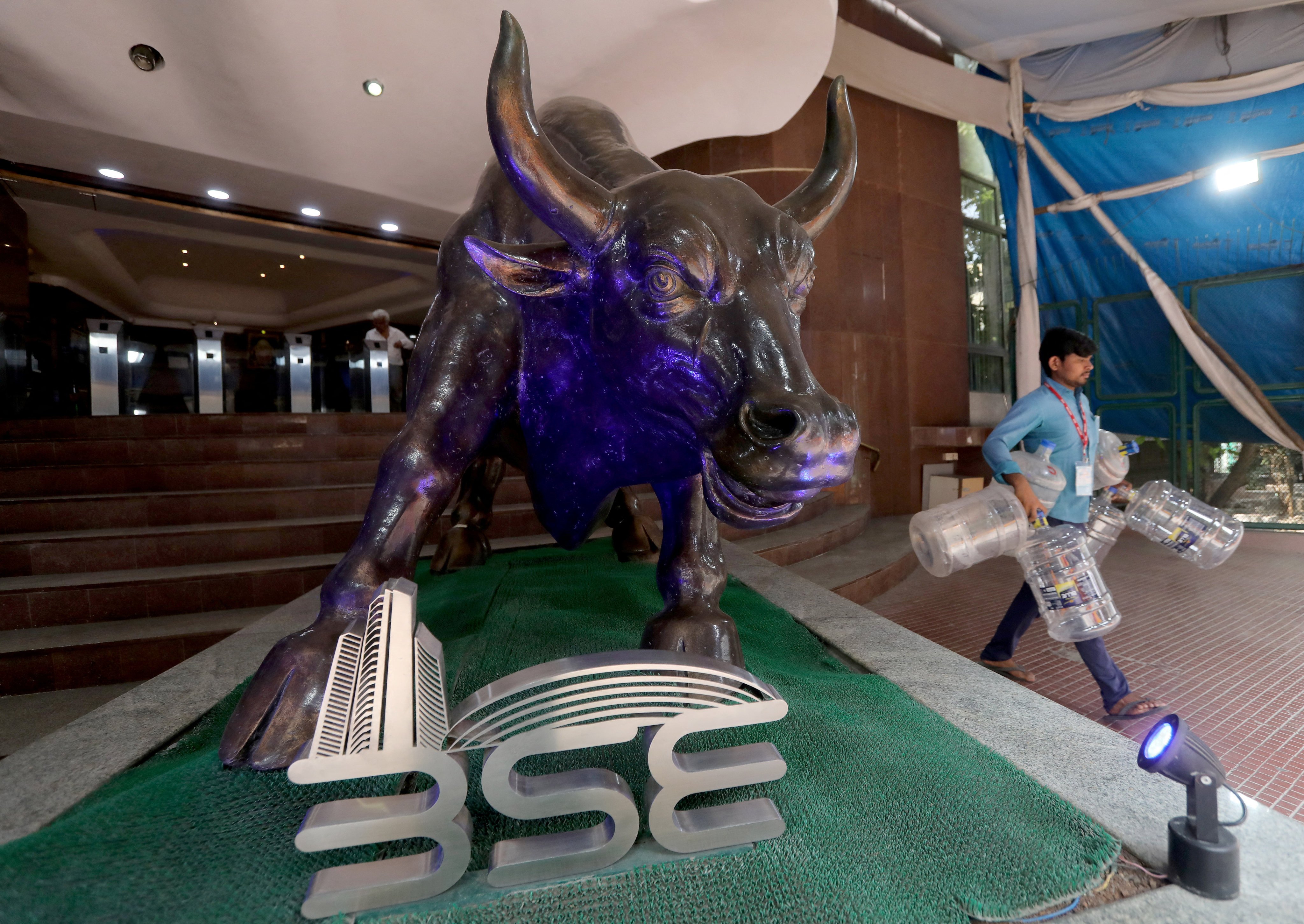 A man carries empty water bottles past a bronze bull statue inside the premises of the Bombay Stock Exchange in Mumbai on February 1, 2023. Photo: Reuters