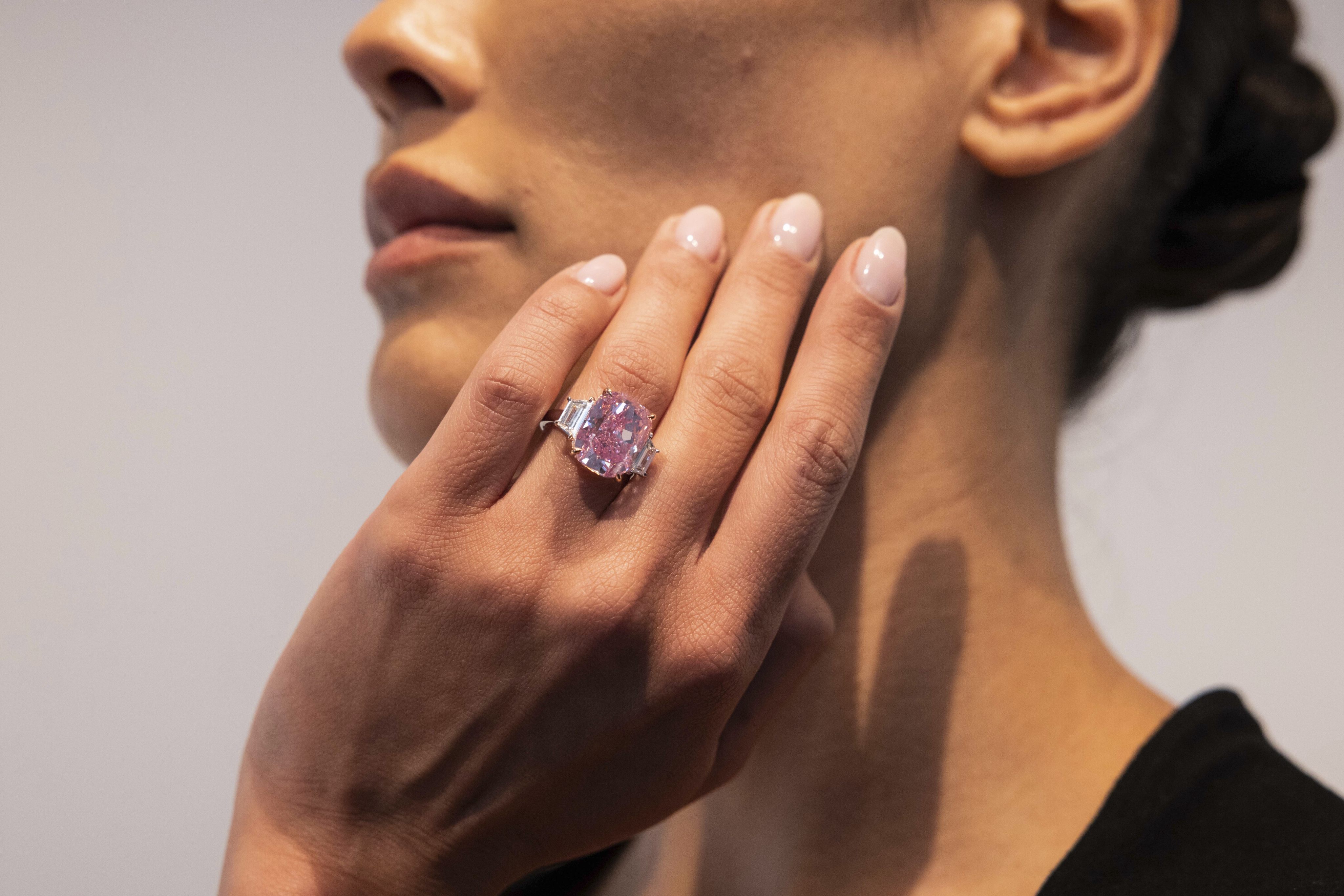 A woman poses with a 10.57 carat pink diamond at Sotheby’s in New York in March. Photo: AP