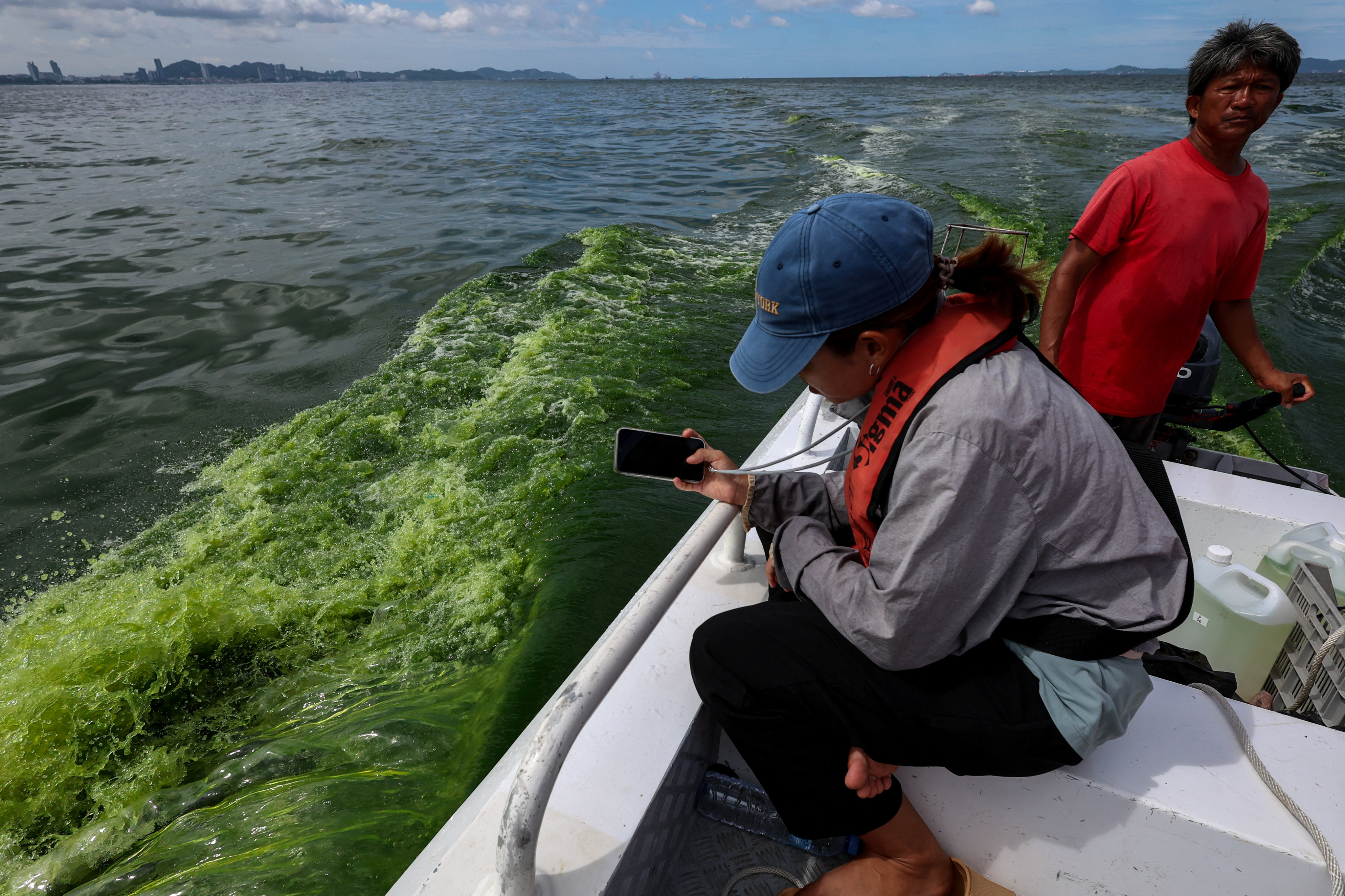 A marine scientist from Thailand’s Kasetsart University takes a picture of green sea water caused by a plankton bloom along the Chonburi coastline. Photo: Reuters