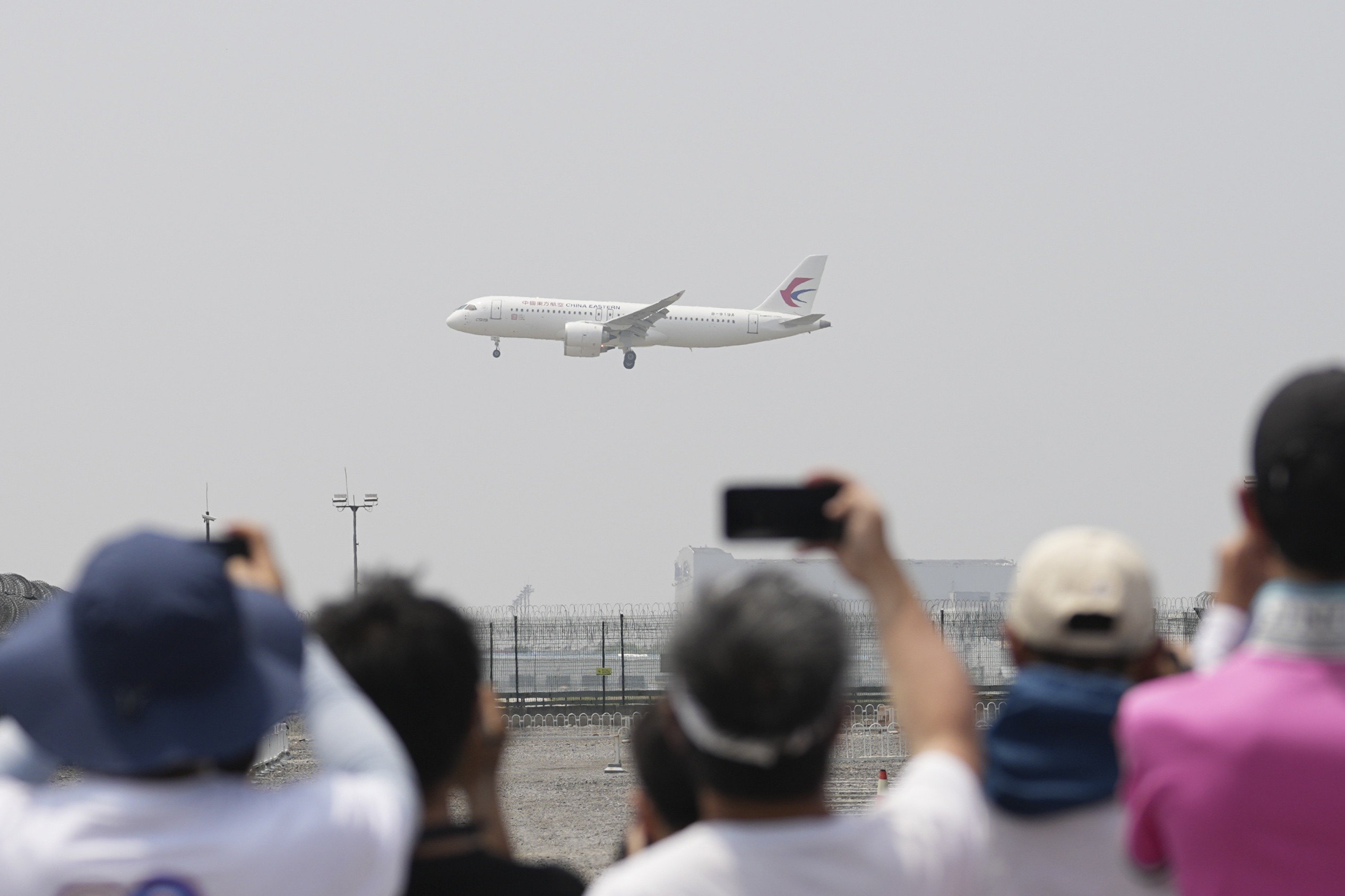 People take photos of a C919 aircraft before it lands at Beijing Capital International Airport on May 28. The plane, China’s signature achievement in domestic aviation production, is being shopped to overseas markets as a symbol of the country’s progress in the sector. Photo: Xinhua