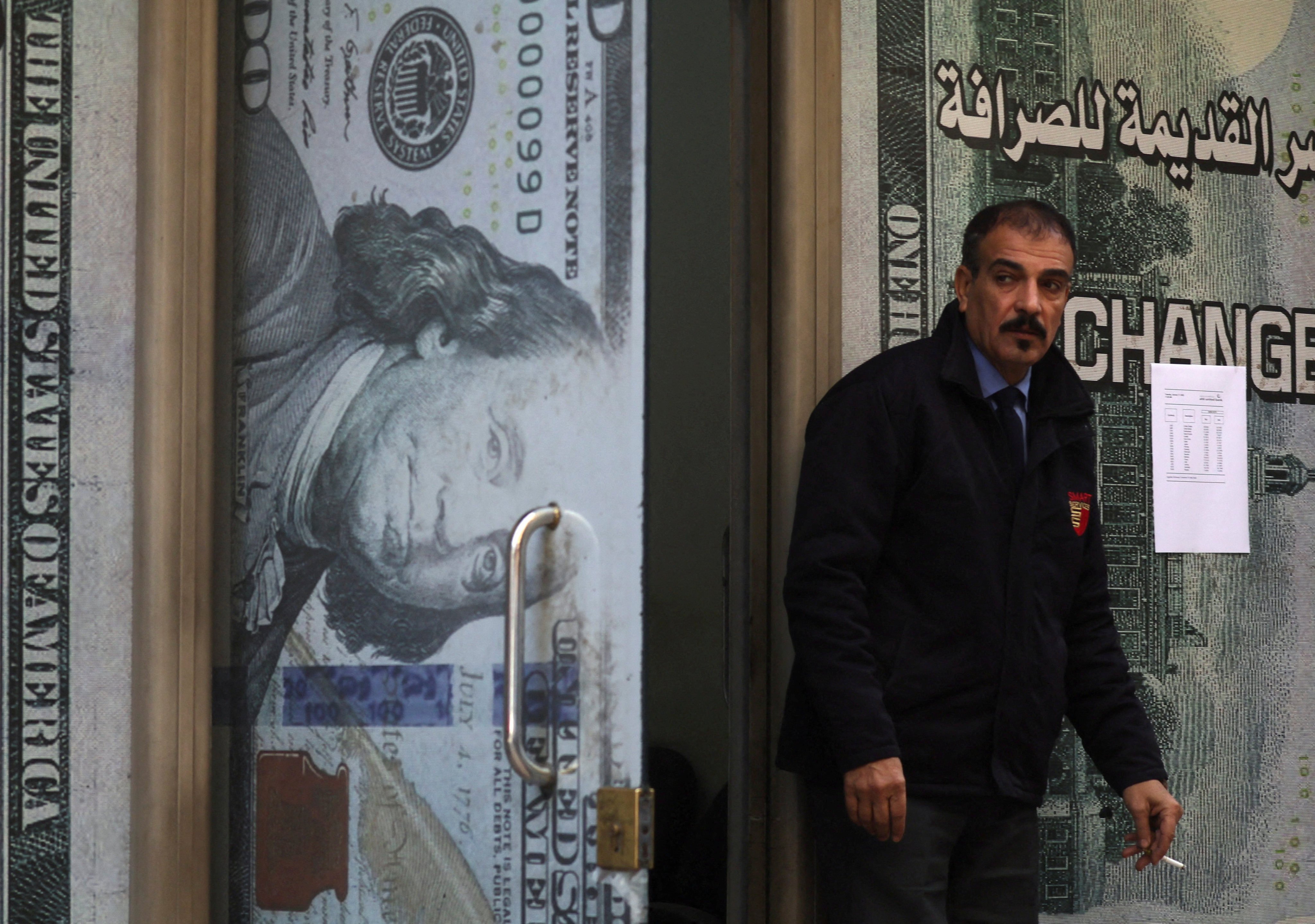 A security guard stands next to a currency exchange bureau advertisement in Cairo, Egypt, on January 17. The logical end to the US debt binge is the collapse of the dollar and rampant inflation. Photo: Reuters