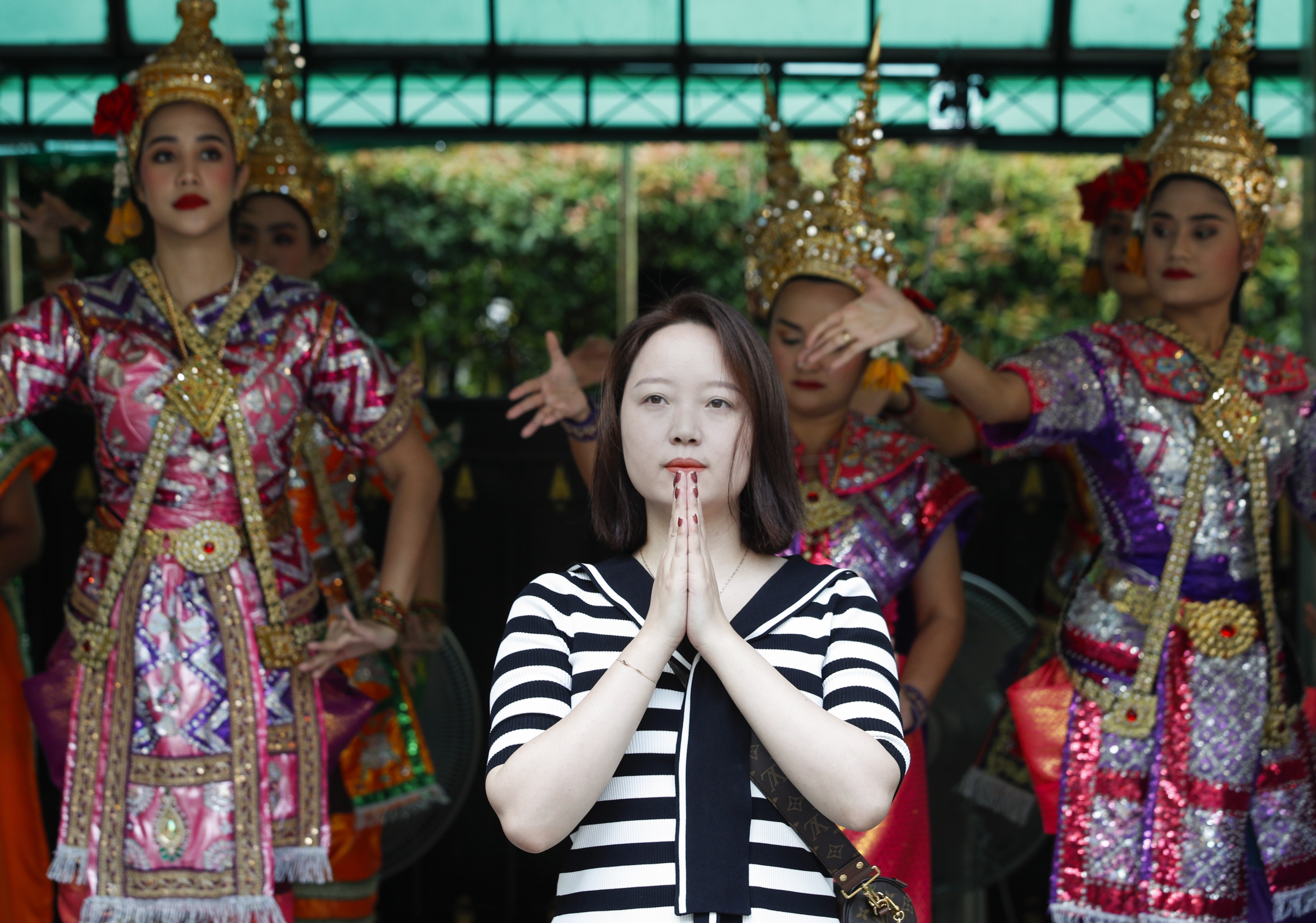 A Chinese tourist praying in front of Thai dancers at the popular Erawan Shrine in Bangkok on Friday. Photo: EPA-EFE