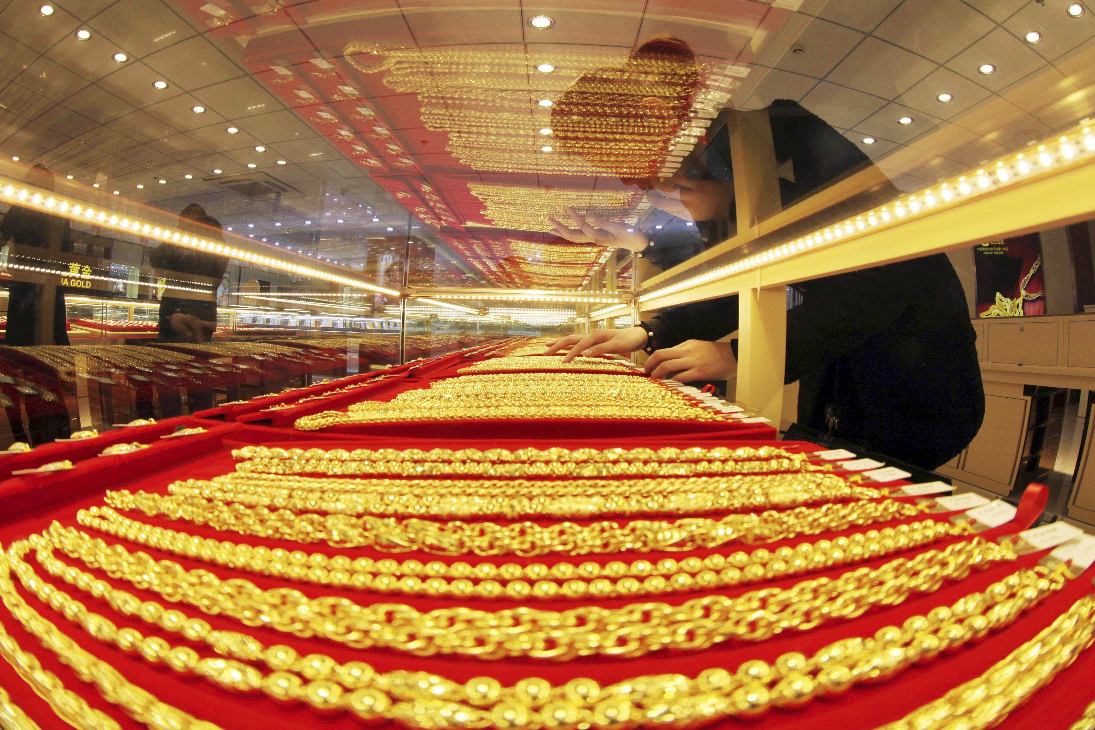A sales assistant arranges gold necklaces at a store in China’s Jiangsu province. Photo: Reuters