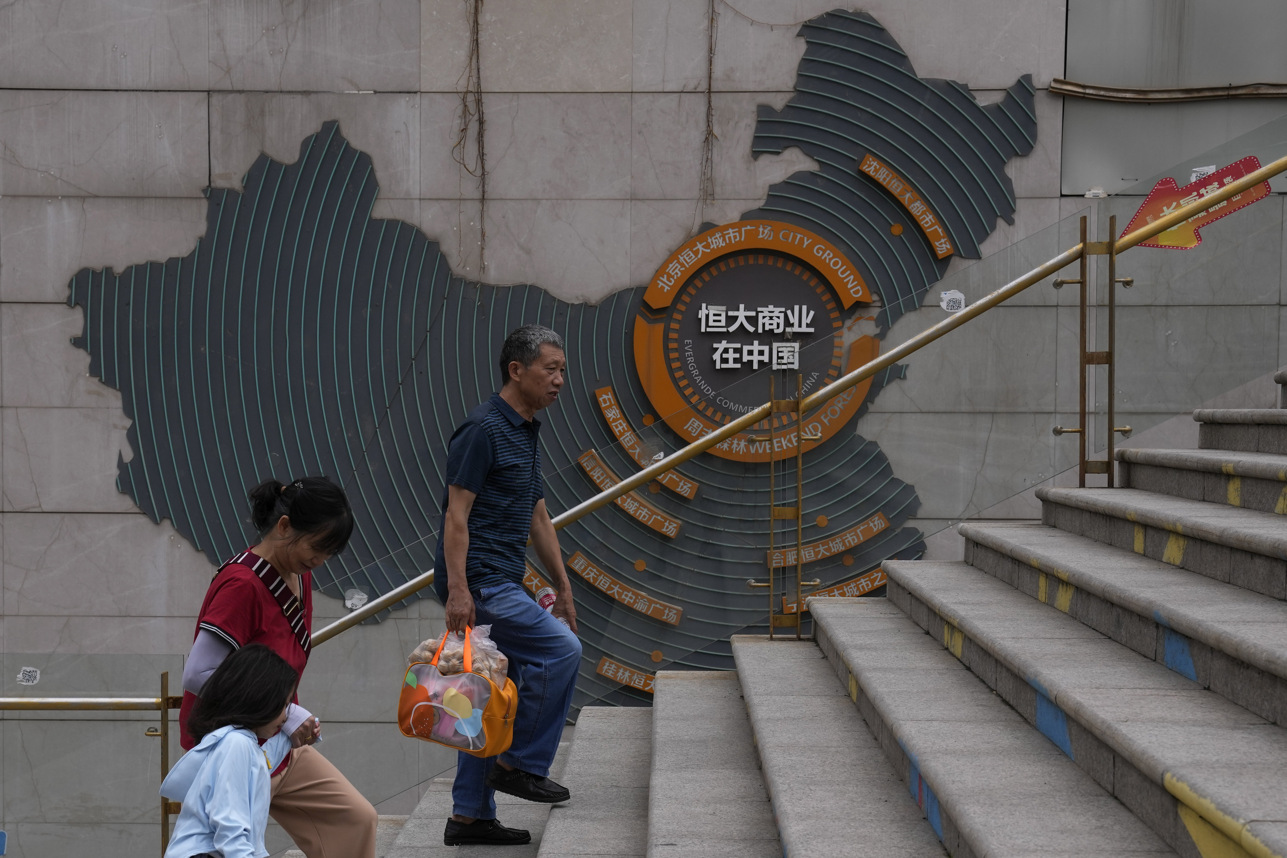 Residents walk past a map showing Evergrande development projects in China. Photo AP