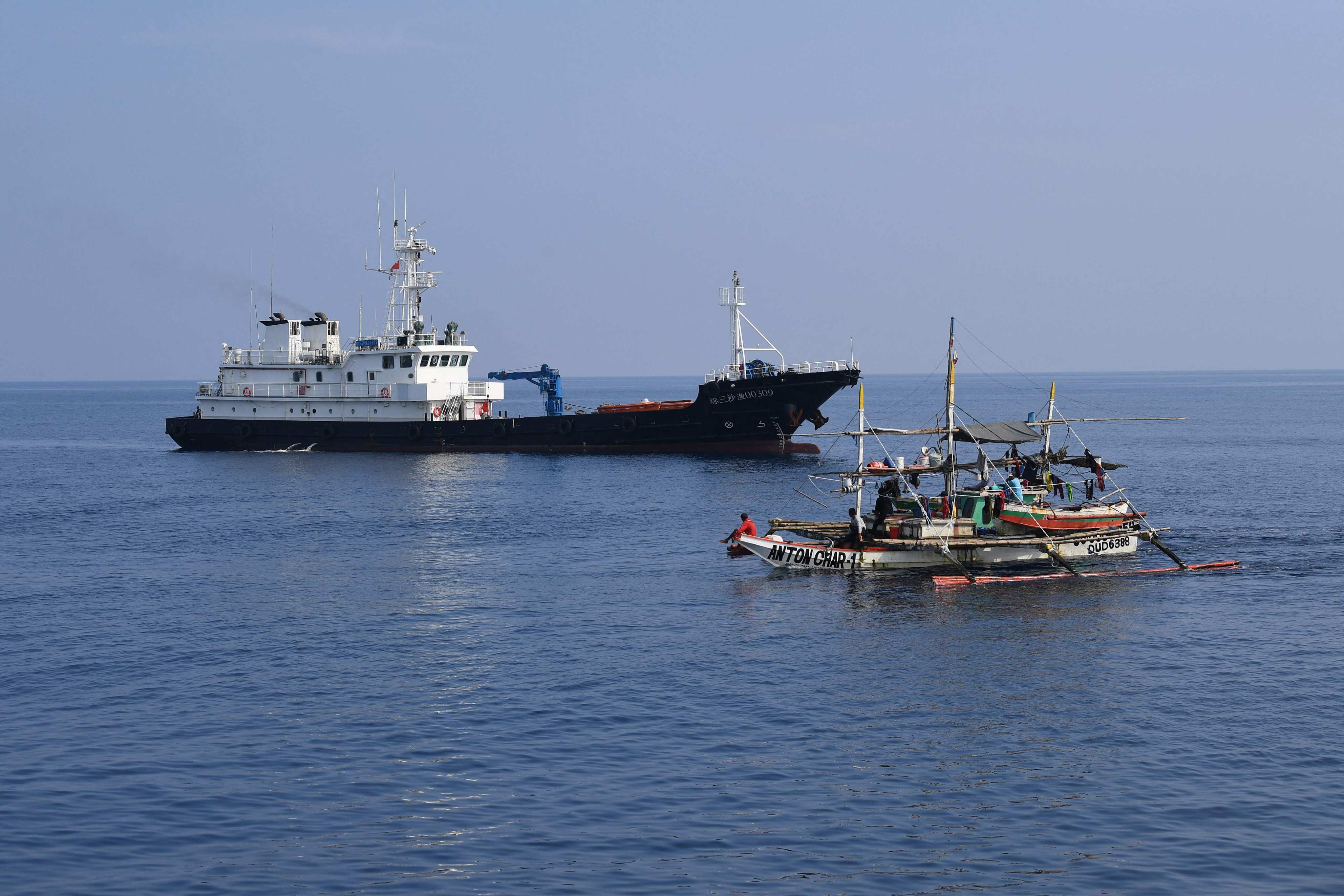 A Philippine fishing boat sailing past a Chinese militia ship near the Chinese-controlled Scarborough Shoal in the South China Sea last Wednesday. Photo: AFP