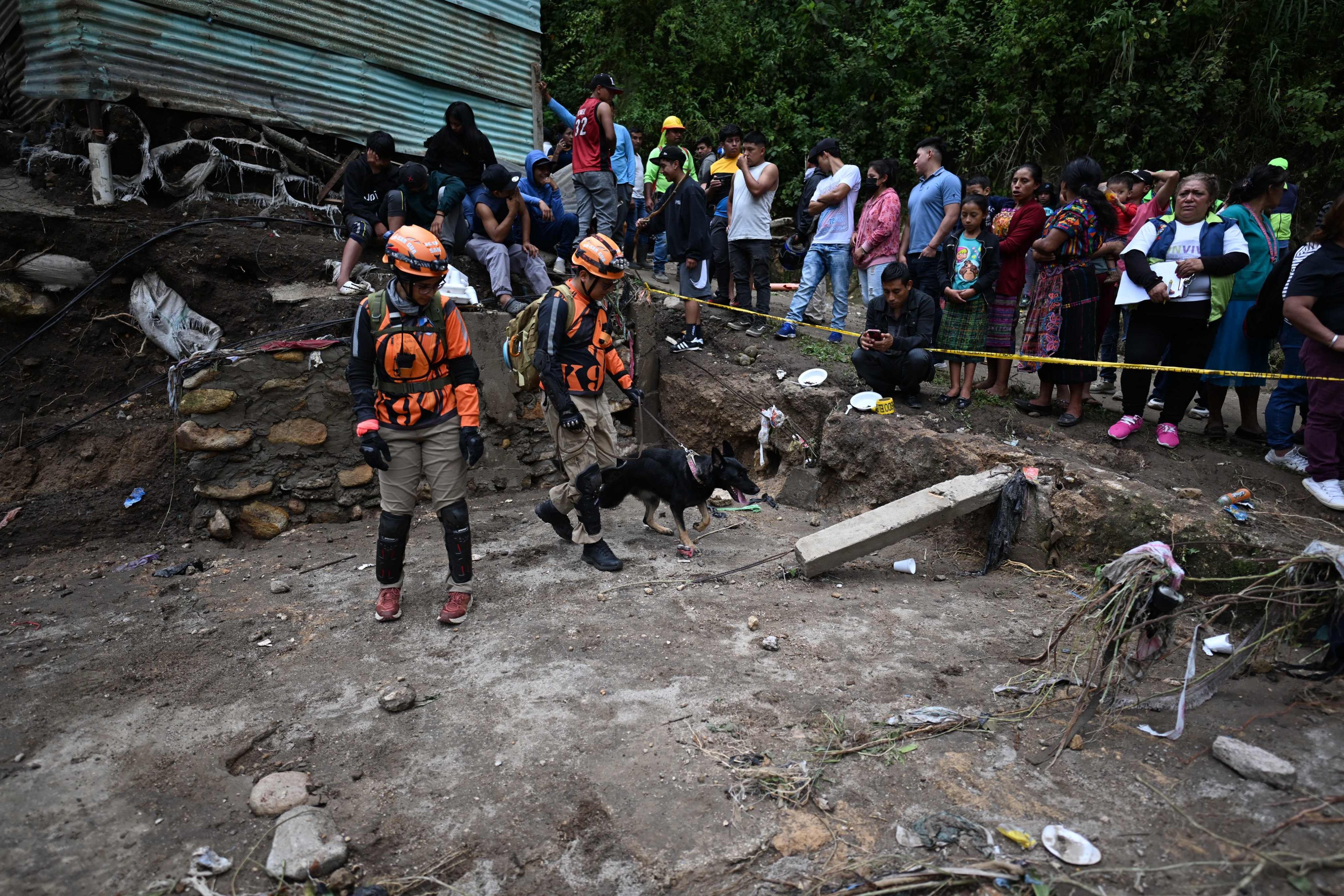 People watch as rescue teams work at the site where a sewage-polluted river swollen by heavy rains swept away precarious homes at Dios es Fiel shantytown, in the Kjell Laugerud colony in Guatemla City on Monday. Photo: AFP