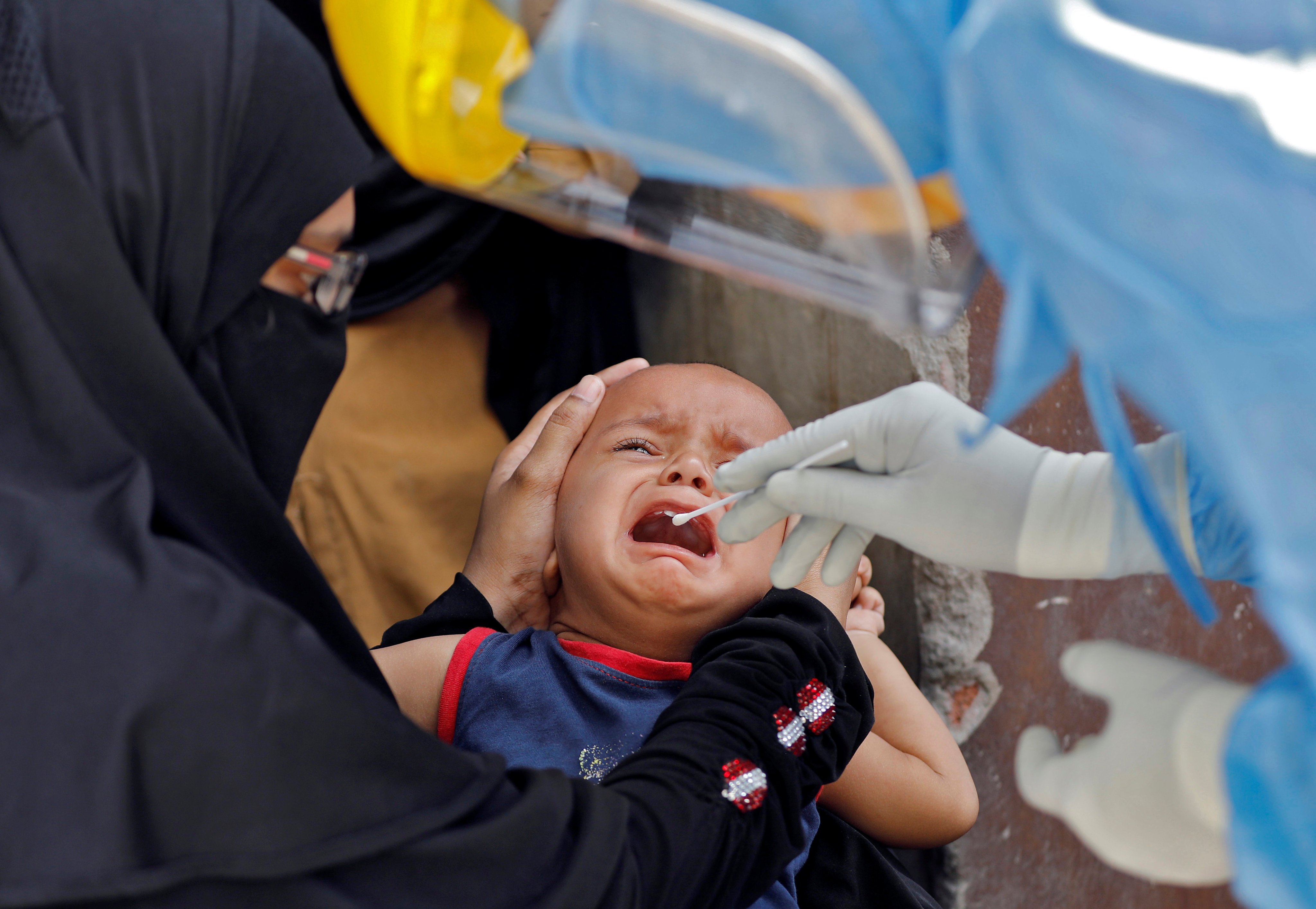 A child cries as a doctor wearing protective gear takes an oral swab for coronavirus testing in Ahmedabad, India, in April 2020. The pandemic set back UN goals for 2030 on a wide variety of issues, including eliminating extreme poverty and hunger. Photo: Reuters