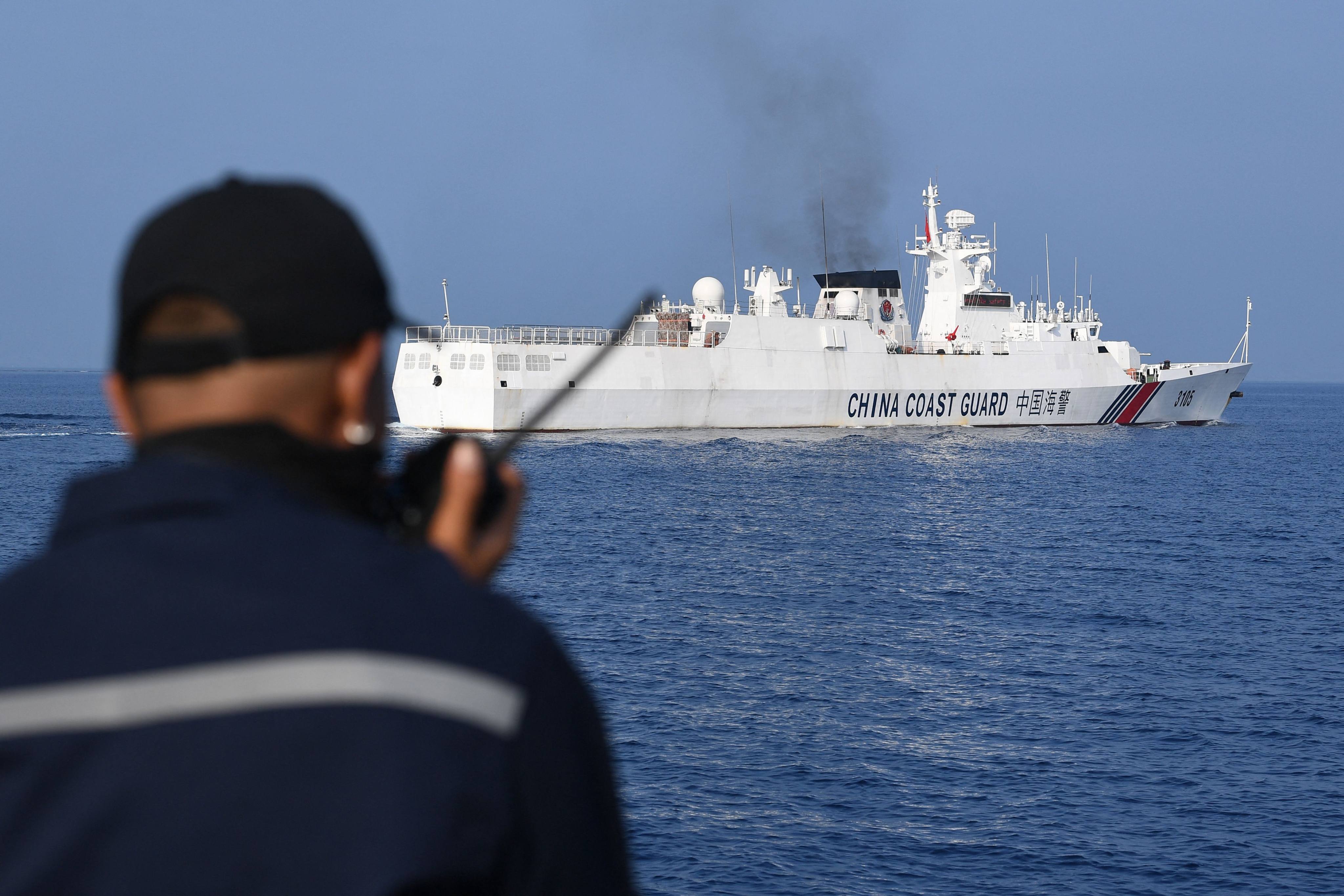 A crew member of the Philippine Bureau of Fisheries and Aquatic Resources ship Datu Bankaw monitors a Chinese coastguard vessel near Scarborough Shoal in the South China Sea this month. Photo: AFP