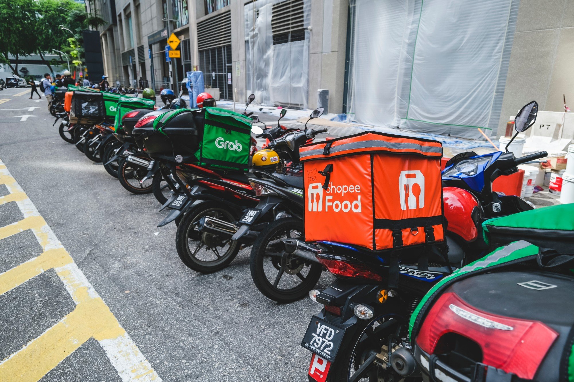 ShopeeFood and GrabFood delivery bags on a row of motorcycles in Kuala Lumpur. Photo: Shutterstock