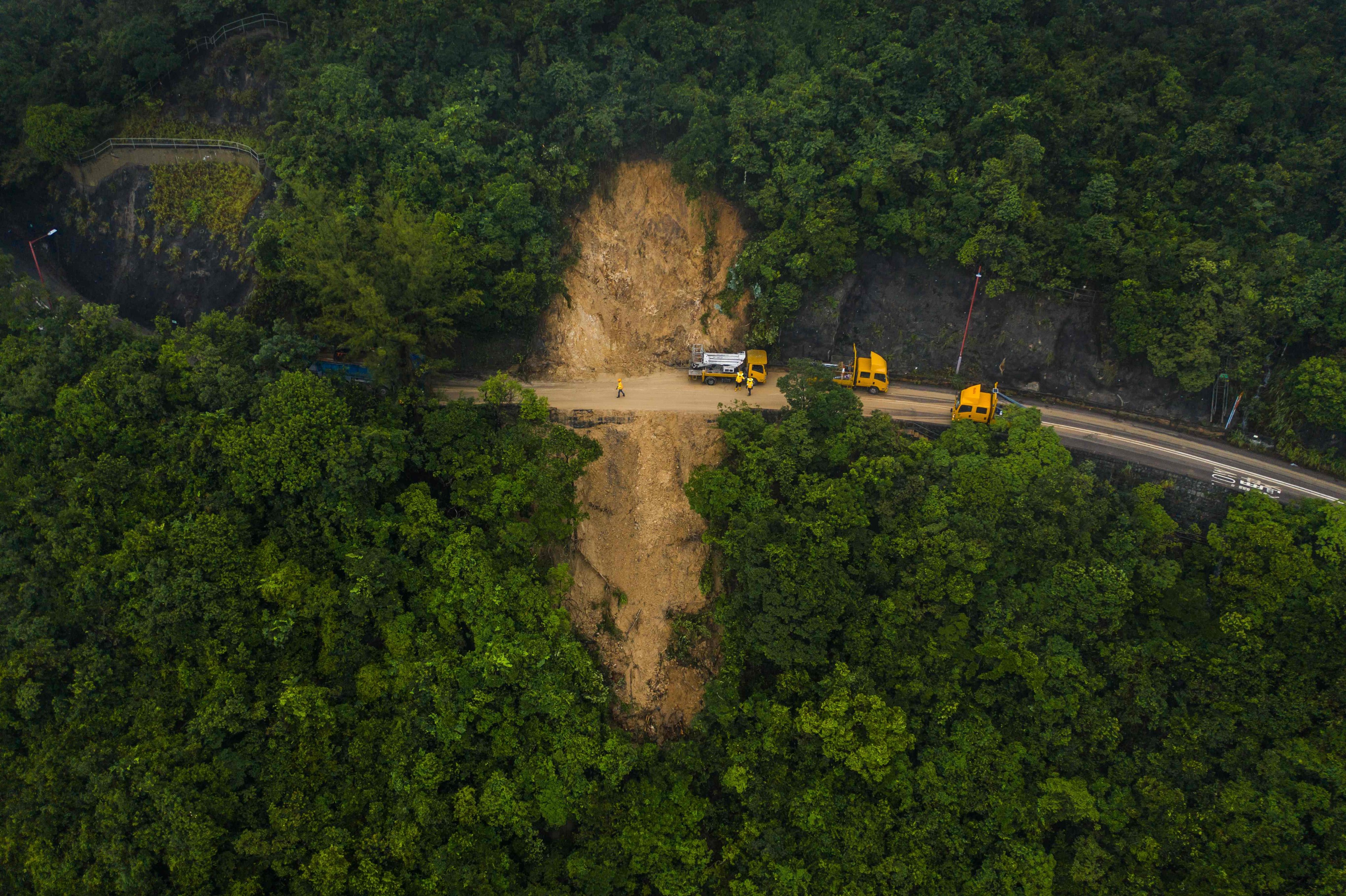 An aerial view of workers clearing a landslide on a closed road leading to the coastal villages of Shek O and Big Wave Bay in Hong Kong on September 9. The flooding and landslides triggered by heavy rain last month exposed problems with the city’s drainage system and emergency response that we must solve in preparation for the next big storm. Photo: AFP