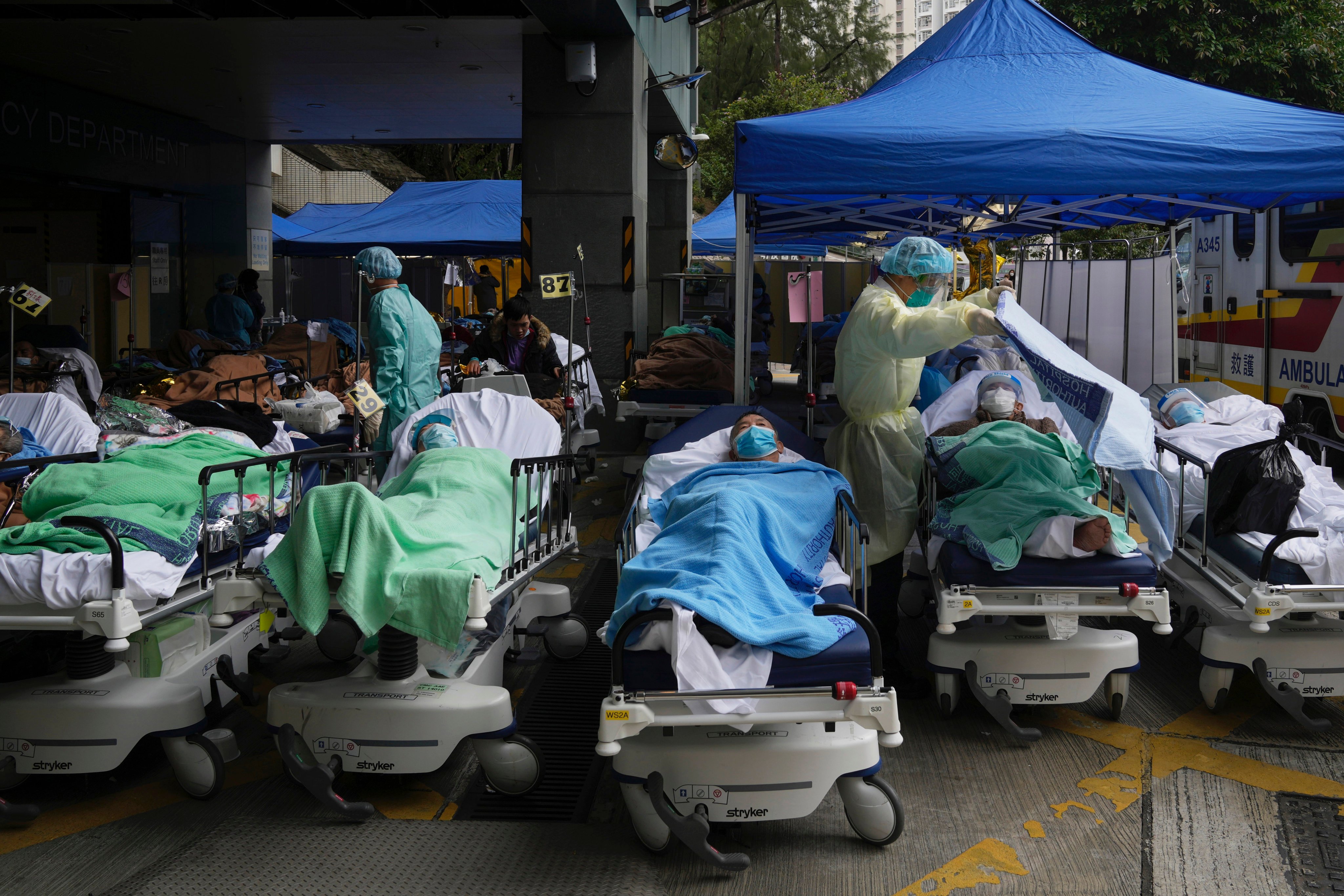 Patients are attented to as they lie on hospital beds at a temporary makeshift treatment area outside Caritas Medical Centre in Hong Kong, on February 18, 2022. Photo: AP 