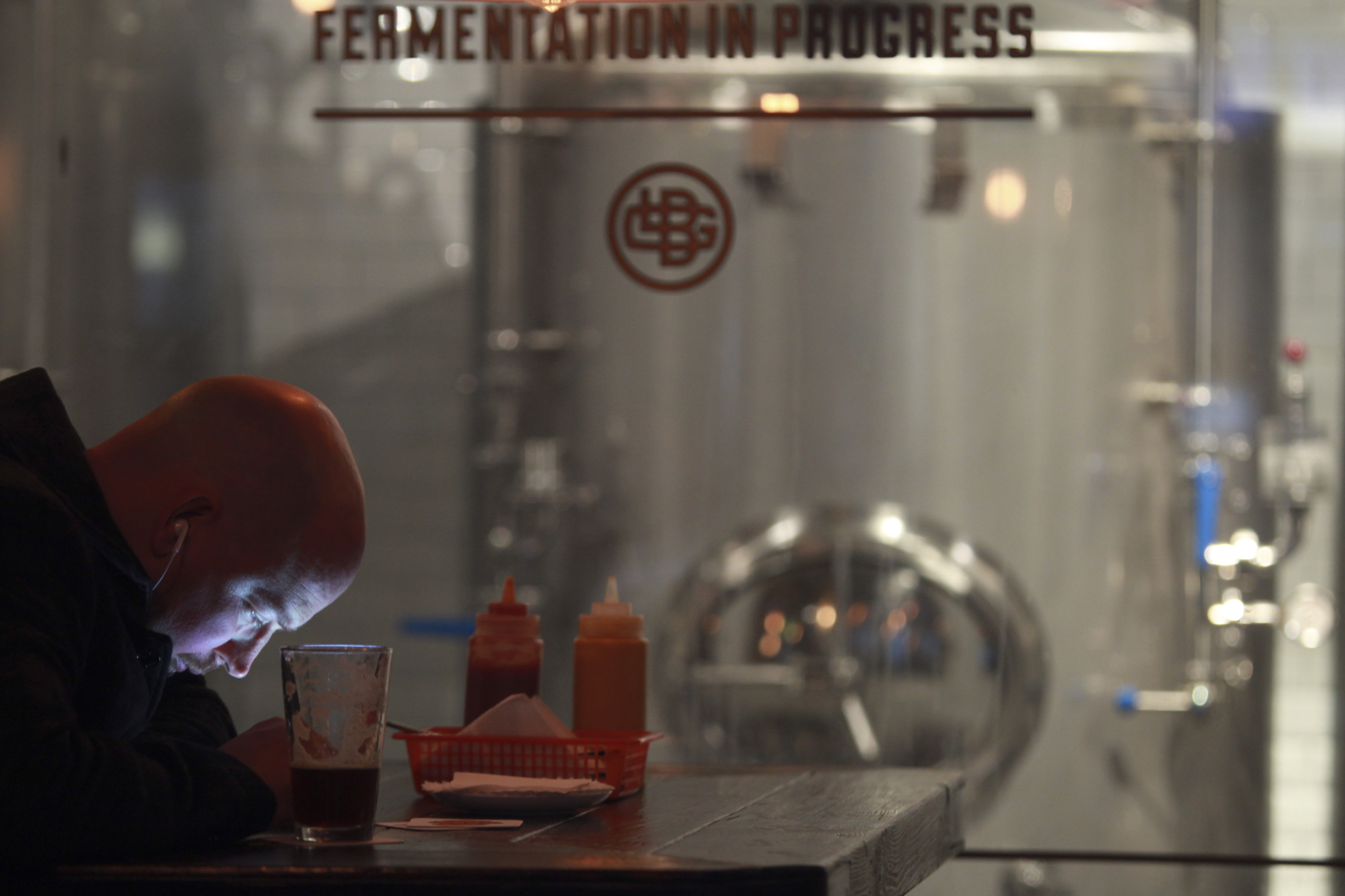 A customer sits in front of the brewing vats at Great Leap Brewing in Beijing on November 1, 2013. Photo: SCMP