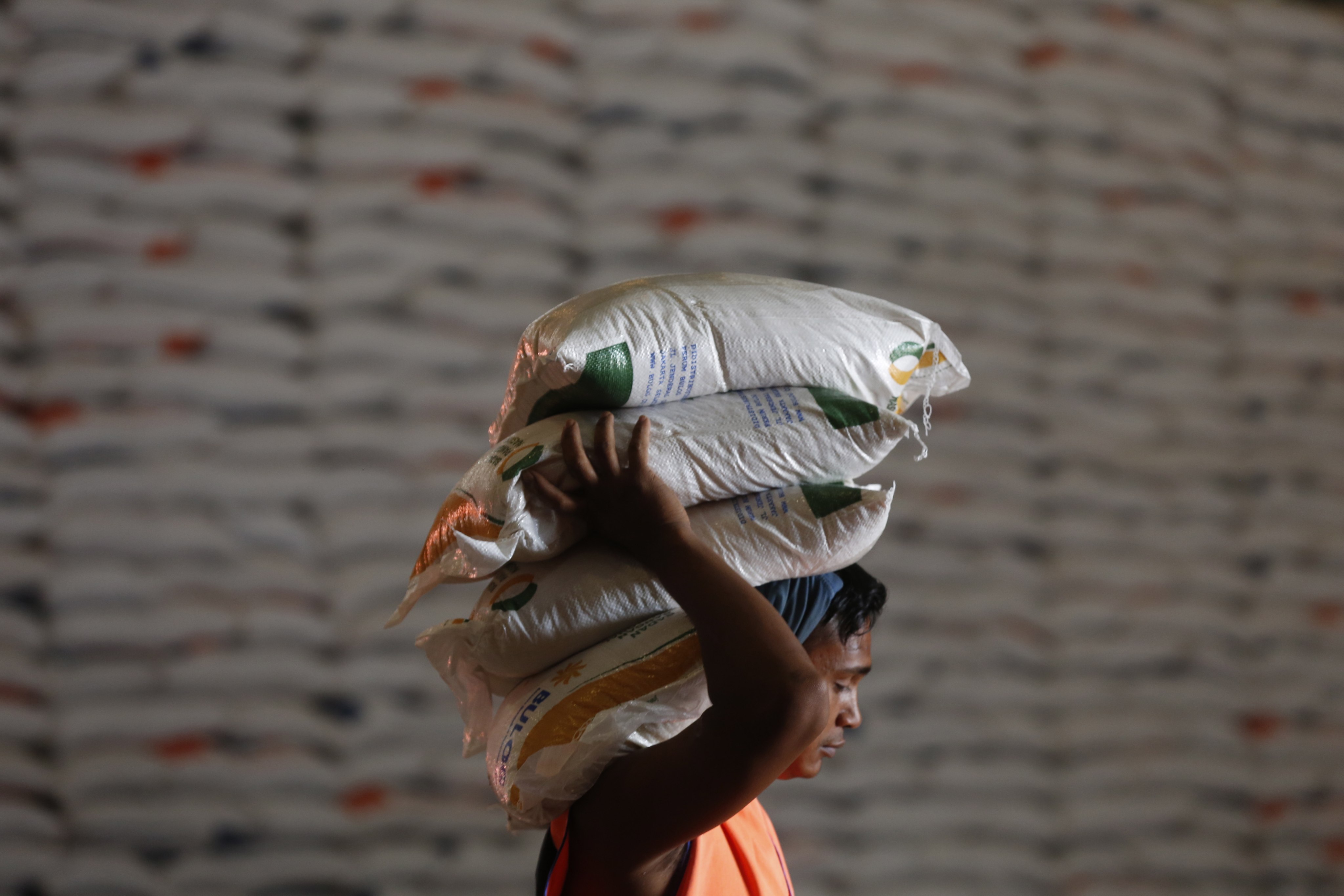 An Indonesian worker carries sacks of rice to be distributed to poor families in Banda Aceh. Photo: EPA-EFE