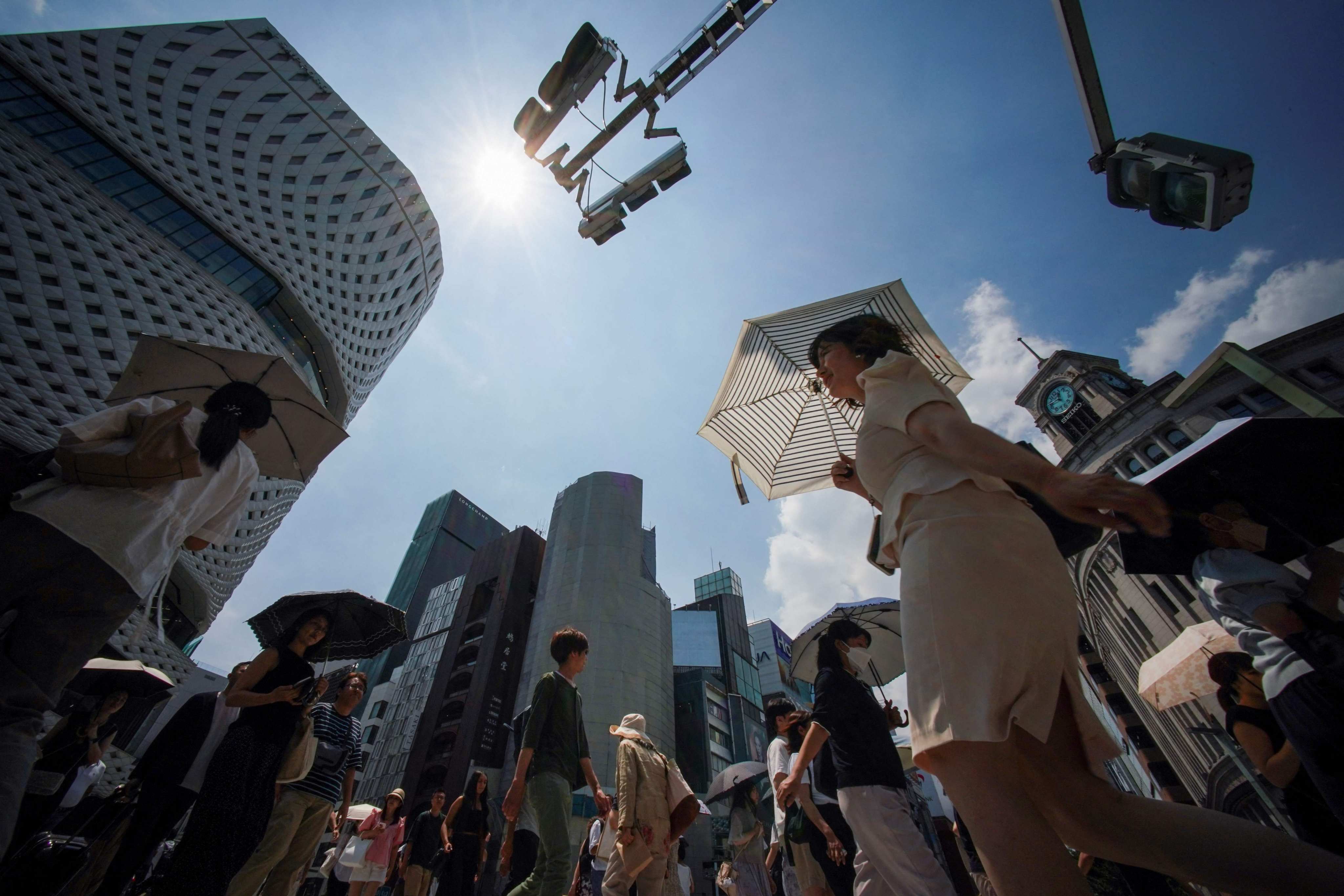 Pedestrians use umbrellas to shelter from the midday sun as they cross a street in Tokyo earlier this year. Photo: AFP