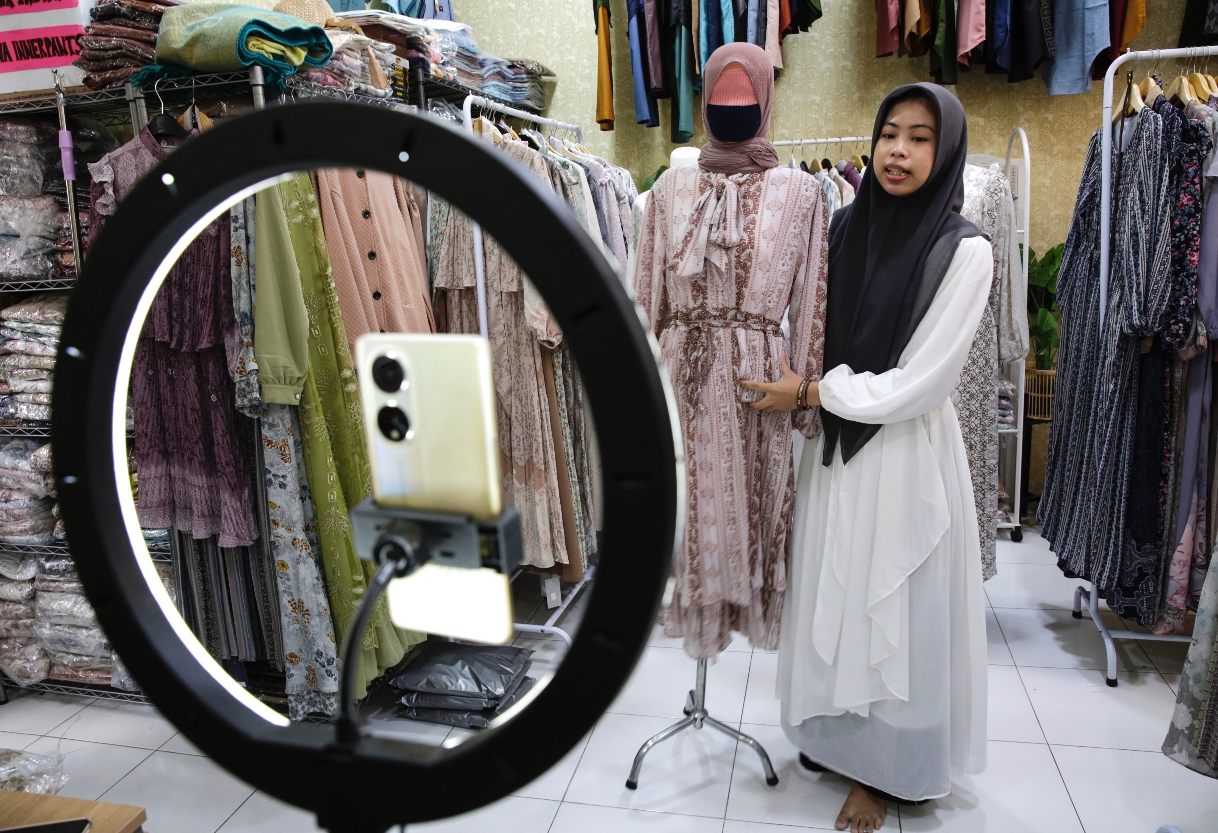 A sales woman showcases a dress as she live-streams on an e-commerce platform at a shop in Depok, Indonesia. President Joko Widodo’s administration has outlawed commercial transactions on all social media platforms. Photo: EPA-EFE