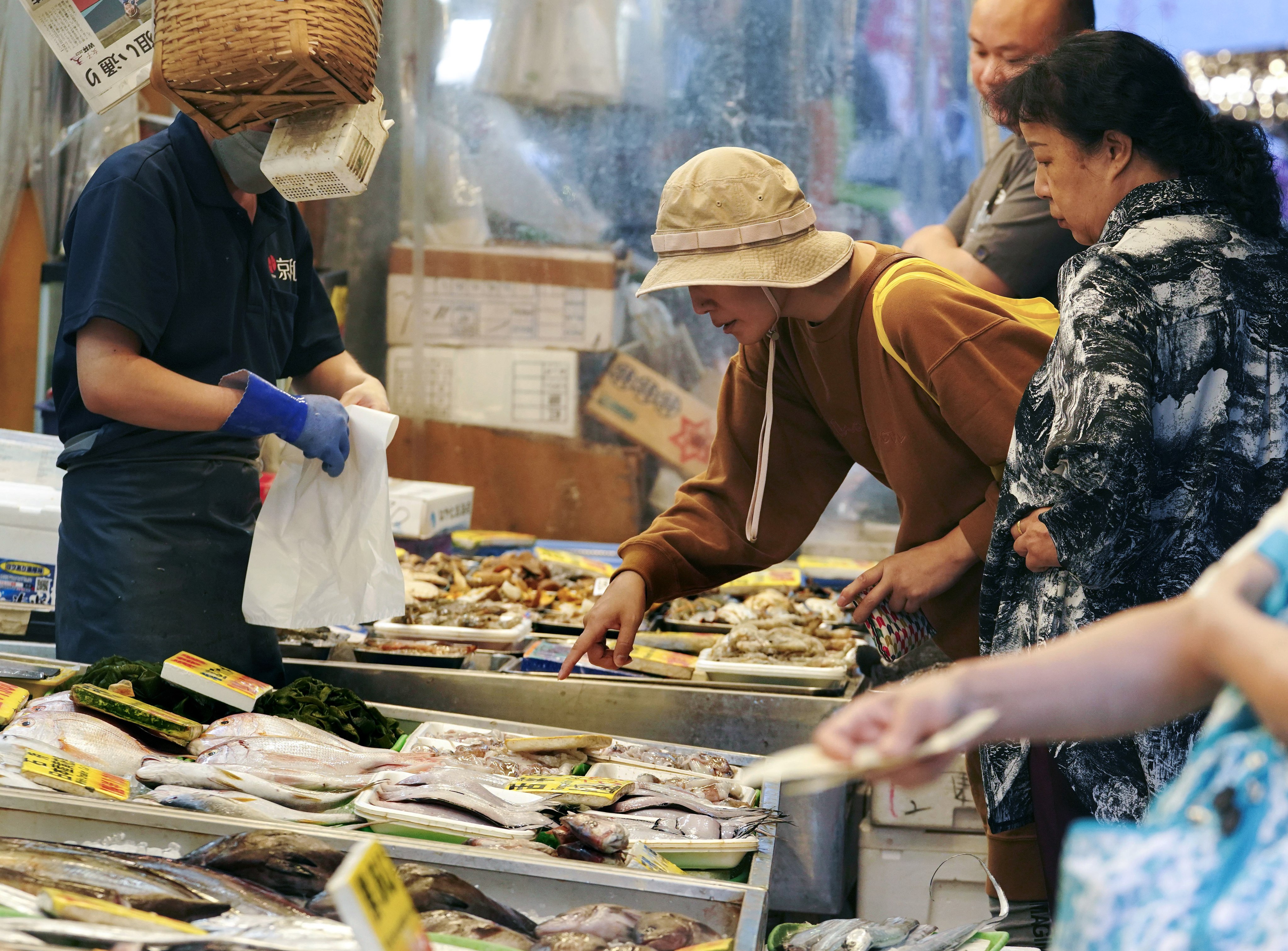 Shoppers examine seafood at a fish store in Tokyo. Photo: EPA-EFE