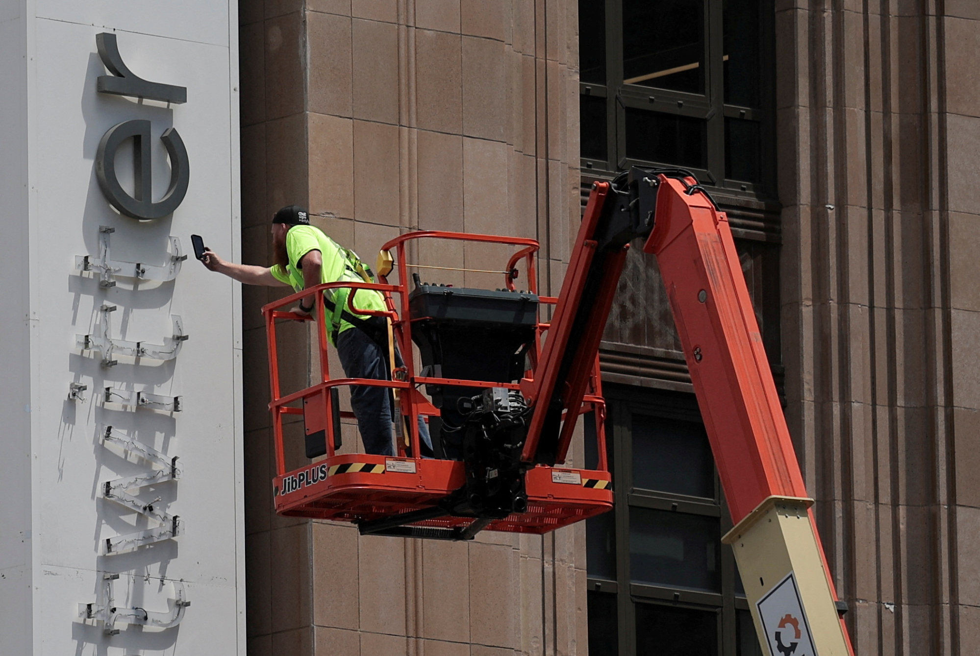 A worker uses a smartphone while dismantling a Twitter’s sign at its corporate headquarters building, after Elon Musk renamed the platform X, in downtown San Francisco on July 24, 2023. Photo: Reuters