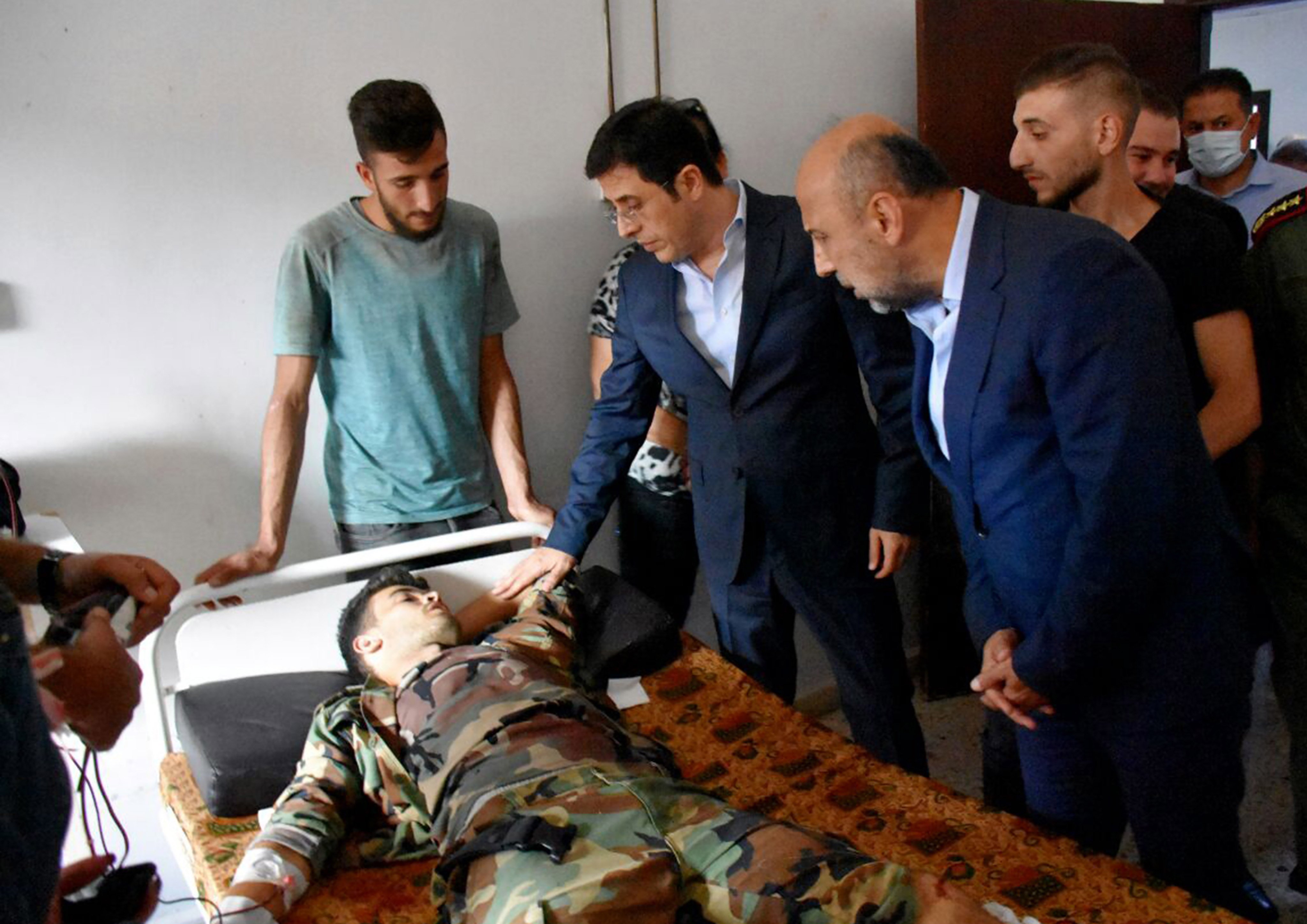 Syrian Health Minister Hassan al-Ghabash (centre) visits a wounded victim of the drone attack. Photo: SANA via EPA-EFE