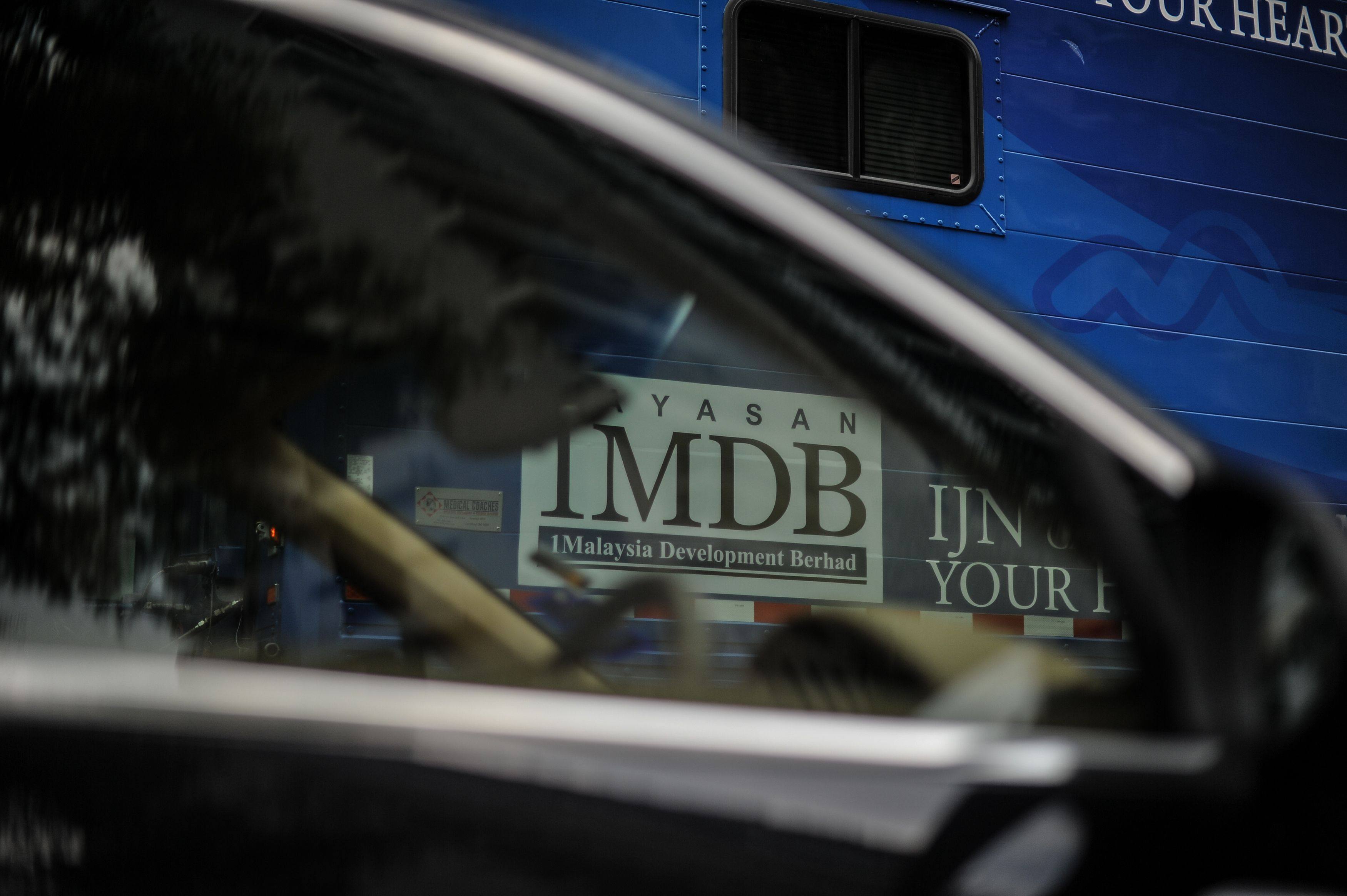 The 1MDB logo is seen through the window of a car in Kuala Lumpur, Malaysia in March 2016. Photo: AFP