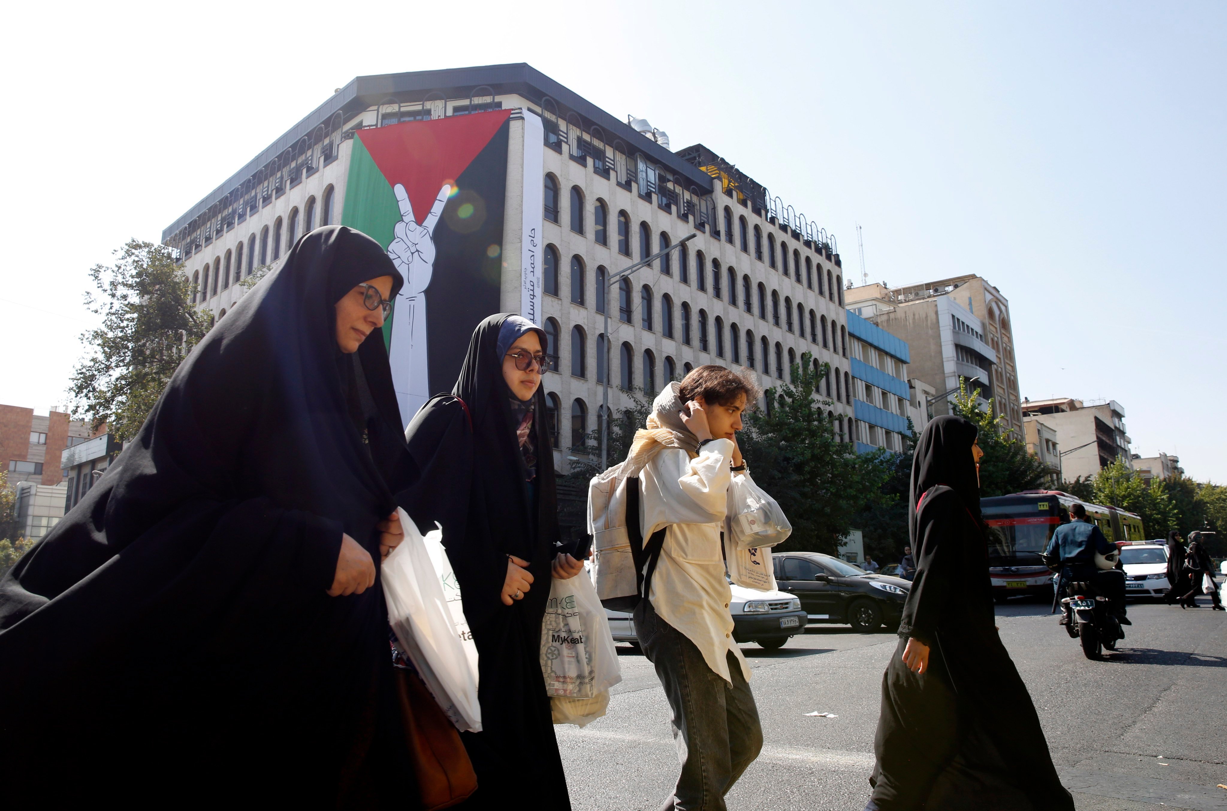 Iranian women walk next to a huge Palestinian flag hanging on a wall in Tehran. The Iranian government openly supported the Hamas attack on Israel and urged the Muslim community to stand by the Palestinians. Photo: EPA-EFE