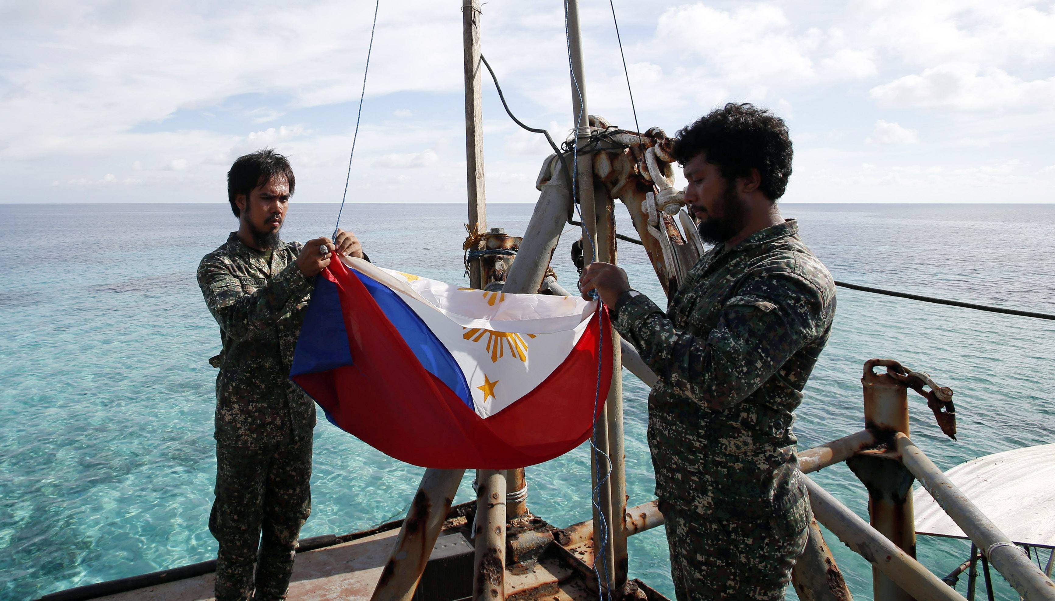 Marines, members of a military detachment stationed aboard the BRP Sierra Madre, fold up a Philippine national flag during a flag retreat on the ship, at the disputed Second Thomas Shoal. Photo: Reuters