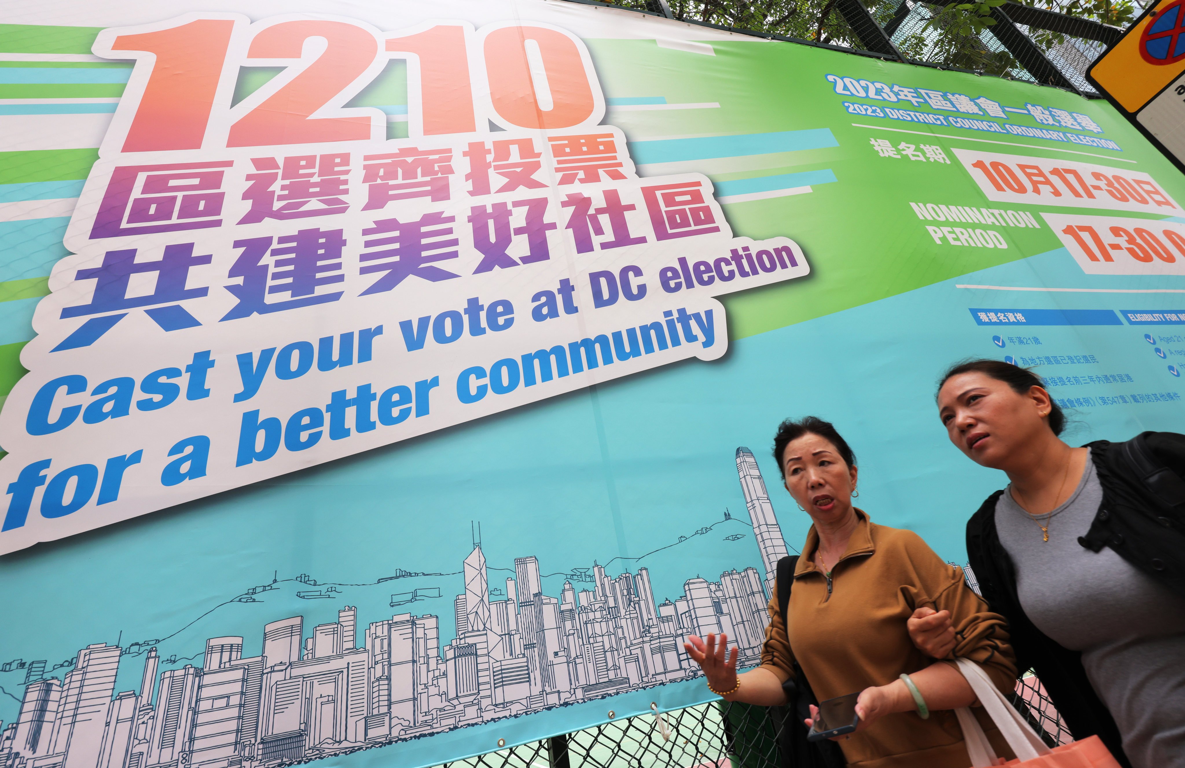 Hongkongers walk past a poster promoting the District Council Election in December. Photo: Jelly Tse