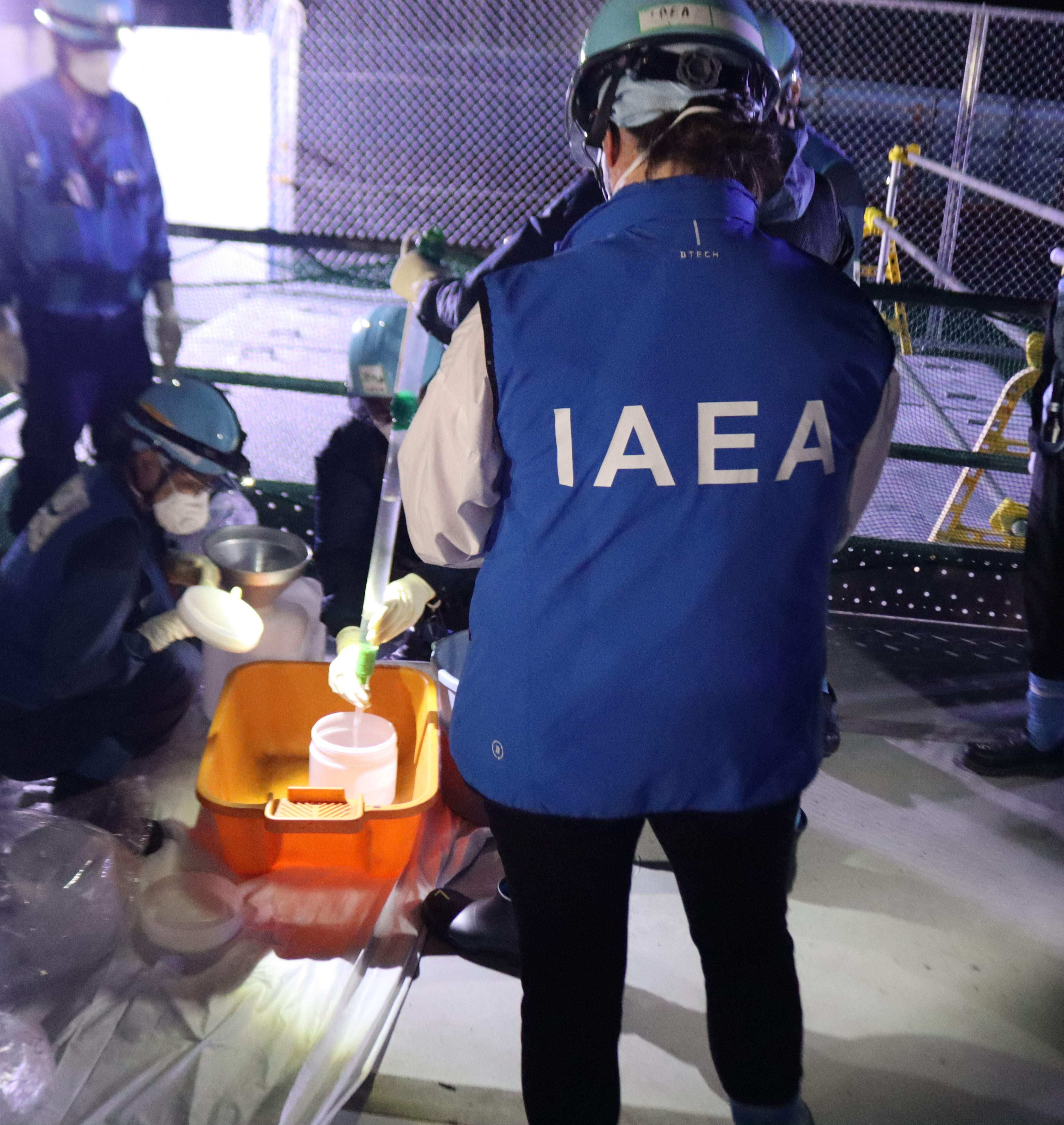 A photo released by TEPCO on August 23 shows International Atomic Energy Agency staff witnessing sampling for the initial release of treated water at the Fukushima Daiichi nuclear power plant in Okuma, Fukushima prefecture. Photo: Handout